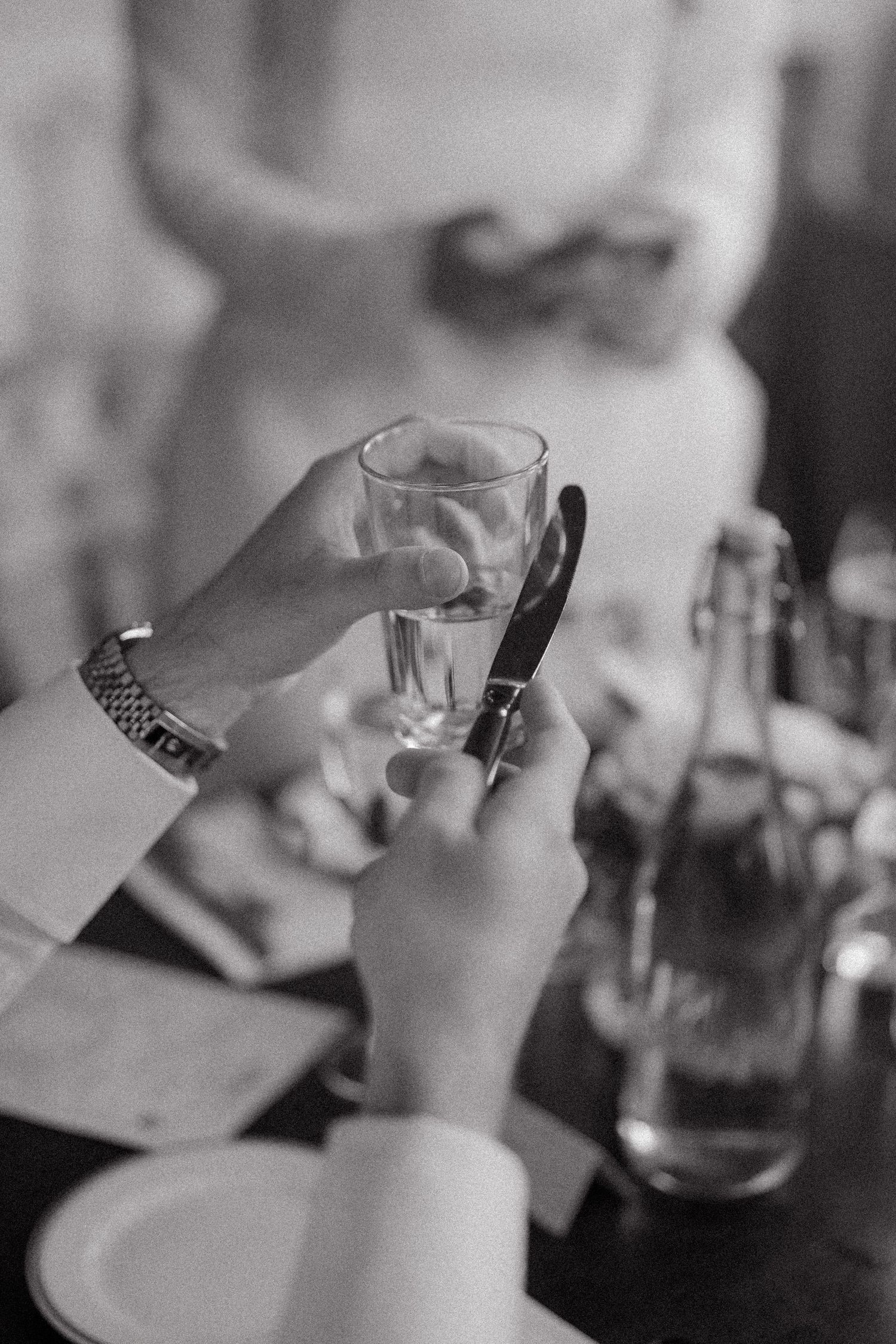 Black and white image of wine glasses and hands during a celebratory toast.