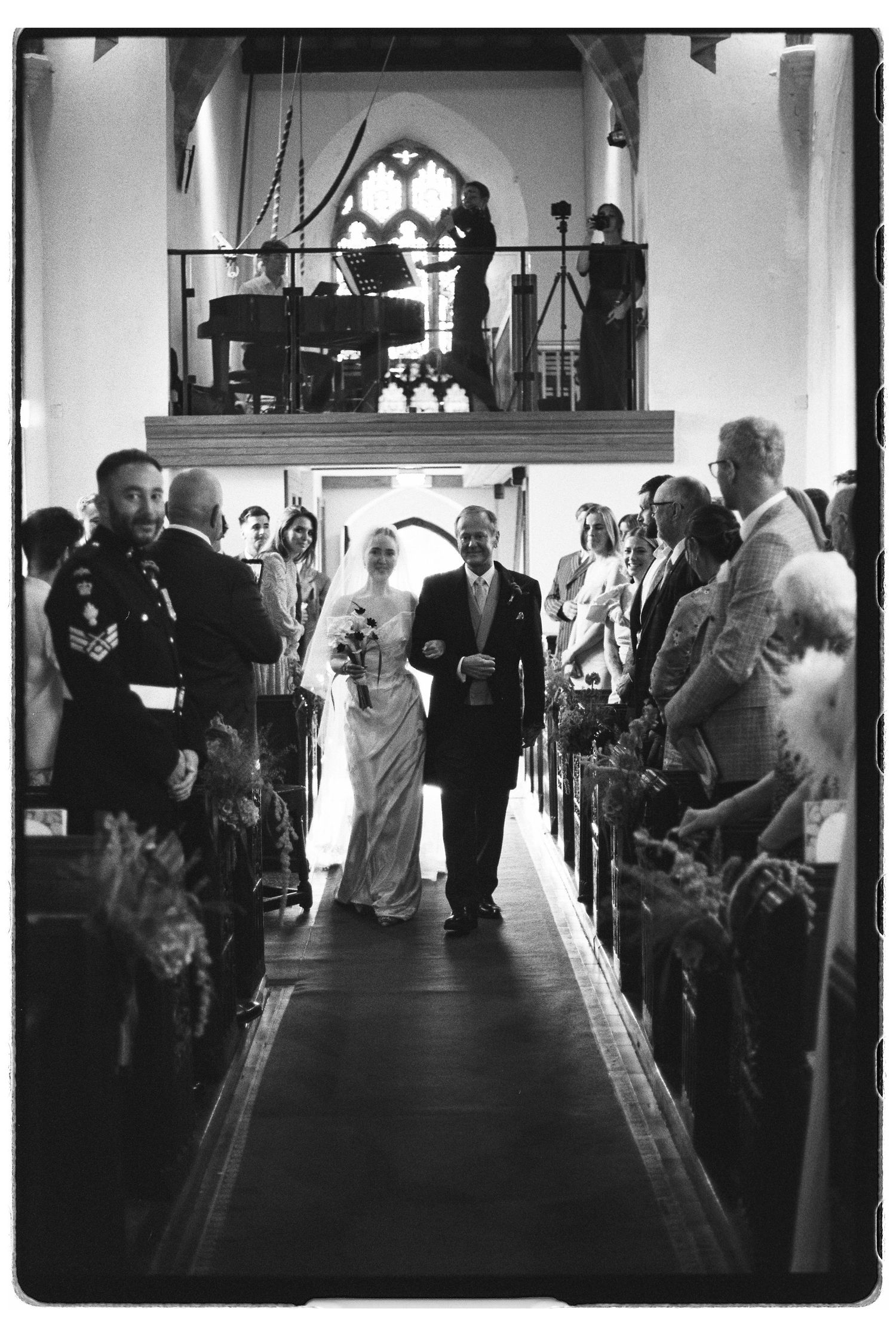 Bride walks down church aisle with father during traditional wedding ceremony.