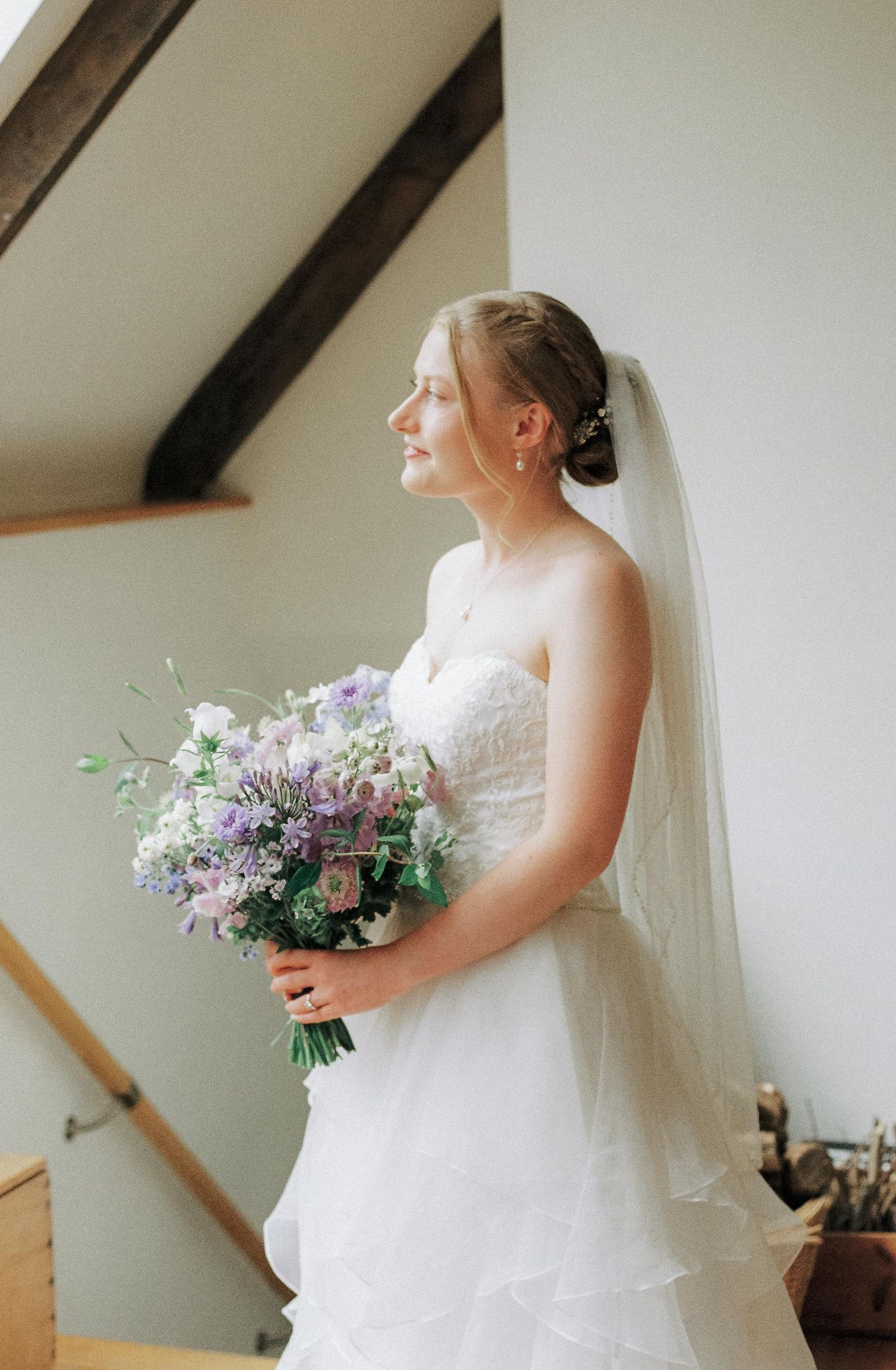 Elegant bridal portrait showing details of a white wedding dress and floral bouquet.