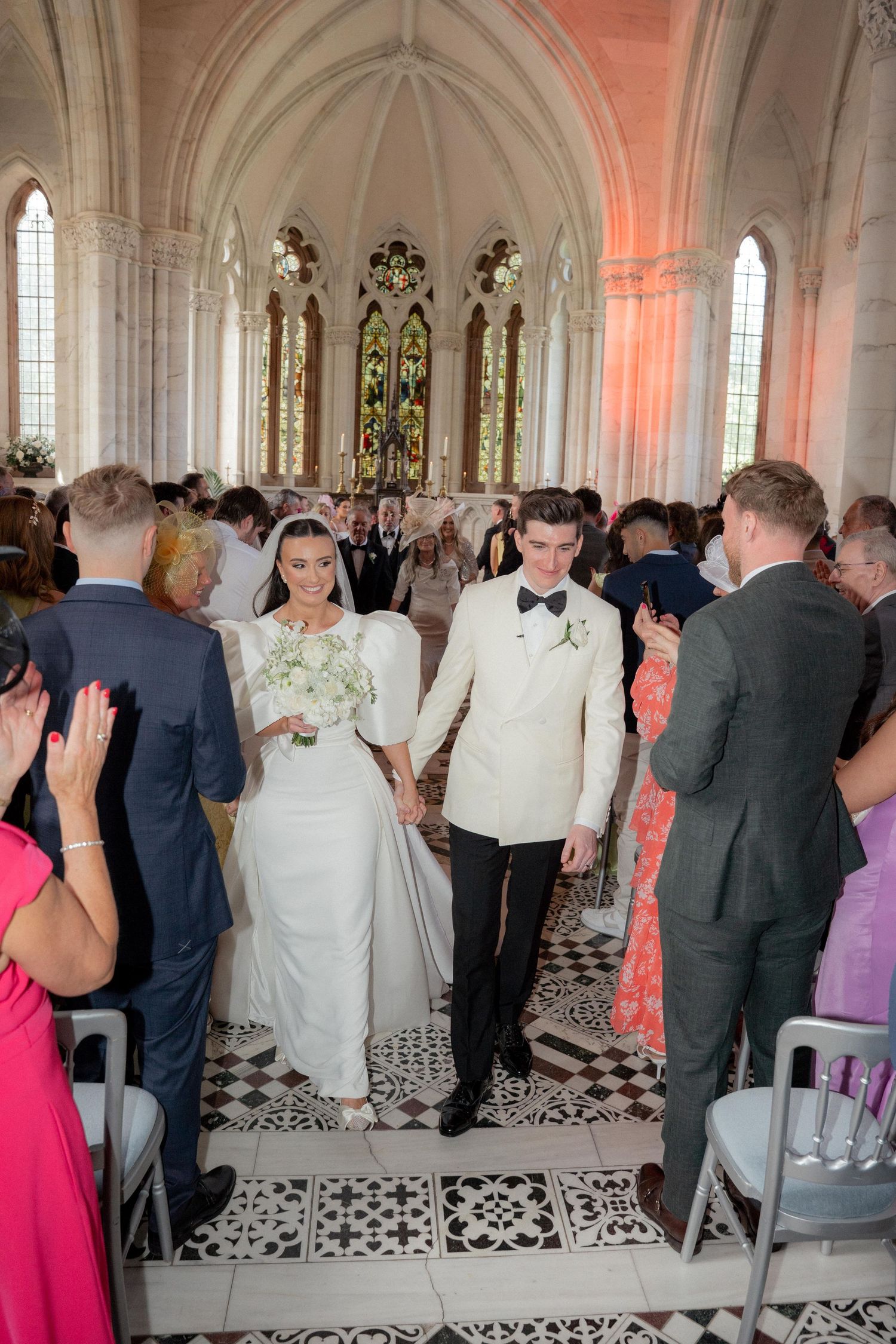 Guests gathered in an elegant cathedral hall with vaulted ceilings and decorative stonework.