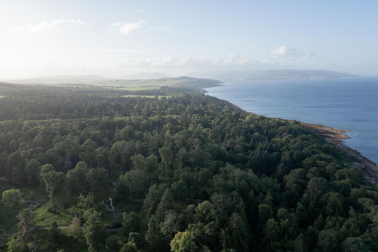 Panoramic coastal view with rolling hills and forests stretching to the horizon.