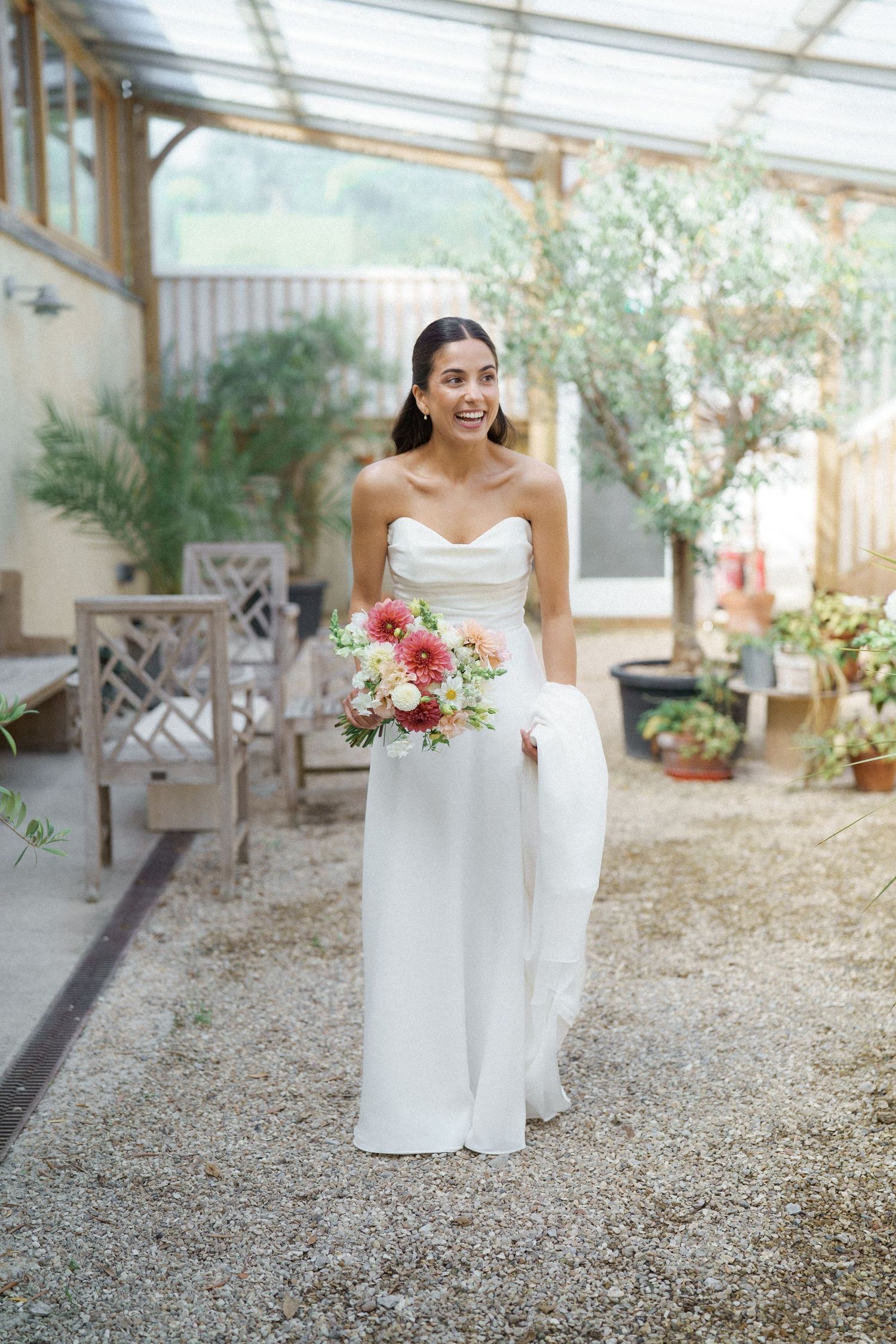 A wedding dress photoshoot in a sunlit greenhouse with potted plants and natural decor.