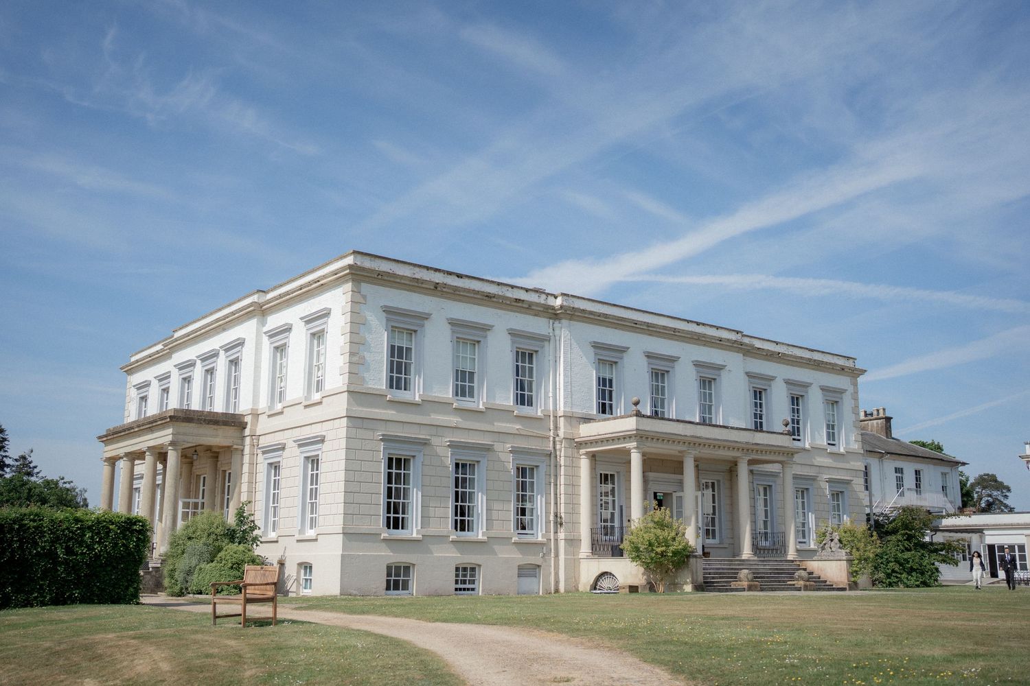 Panoramic view of Buxted Park's grand white mansion exterior on a sunny day.
