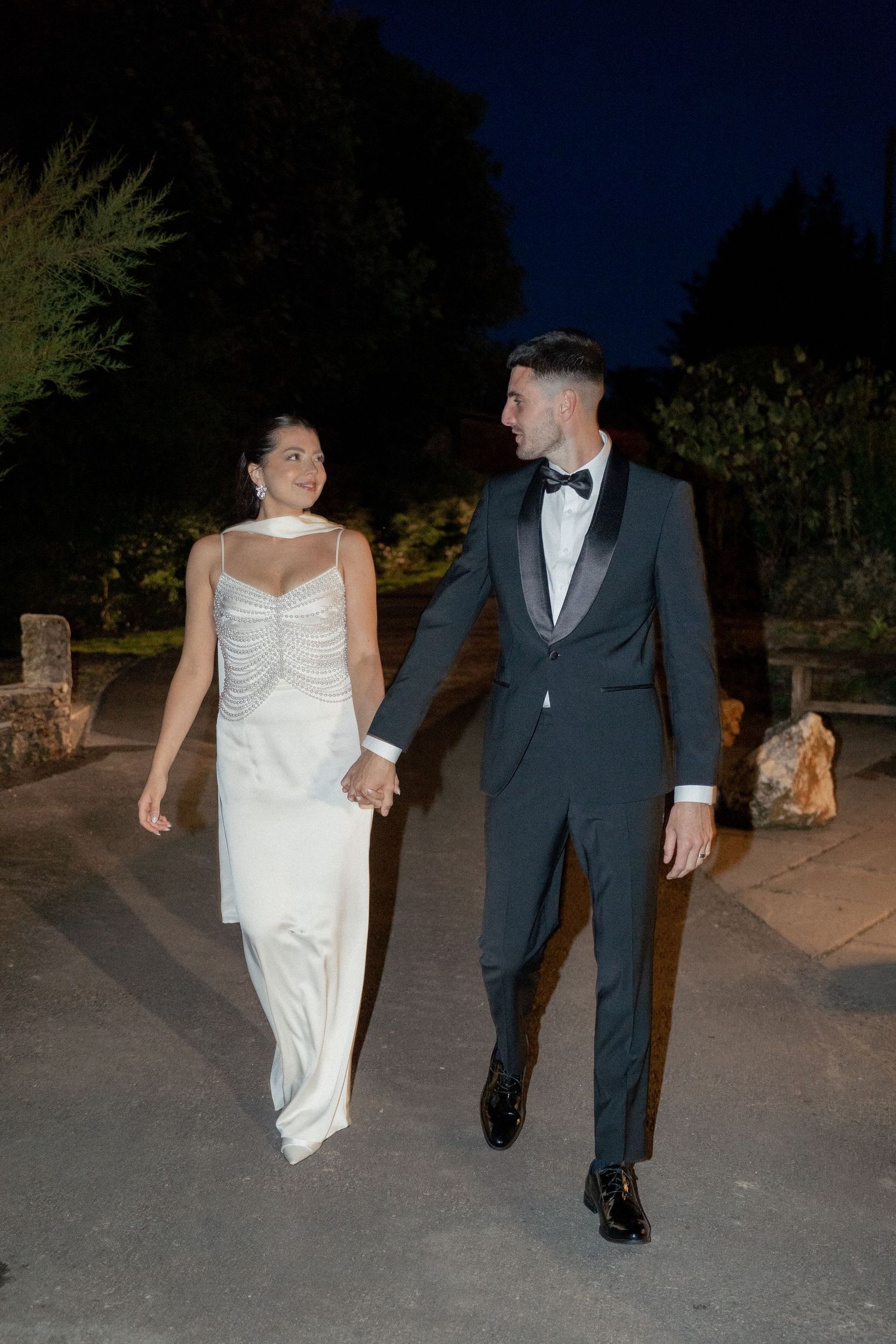 Couple walking together at night after their wedding celebration.
