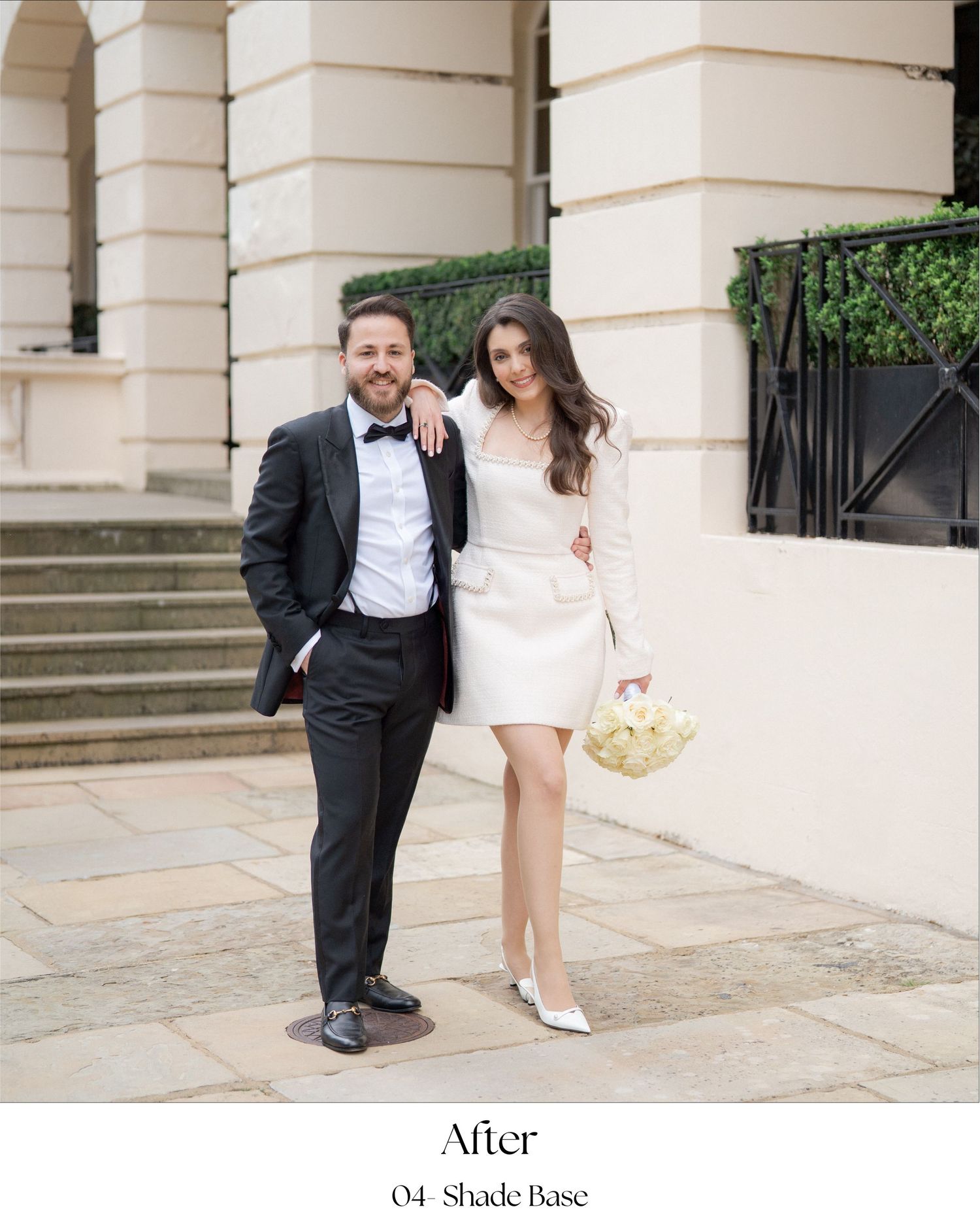 A couple in formal wedding attire poses together on elegant stone steps of a historic building.