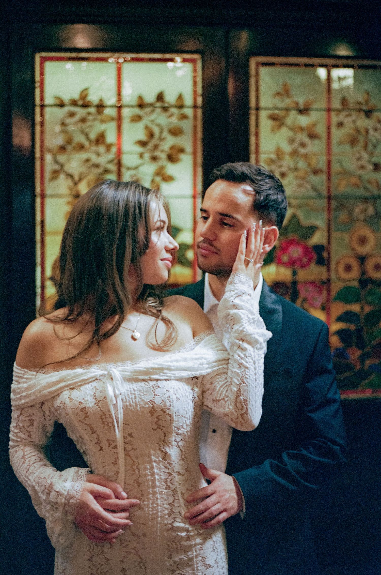 Romantic couple shares intimate dance moments in formal attire against decorative background.