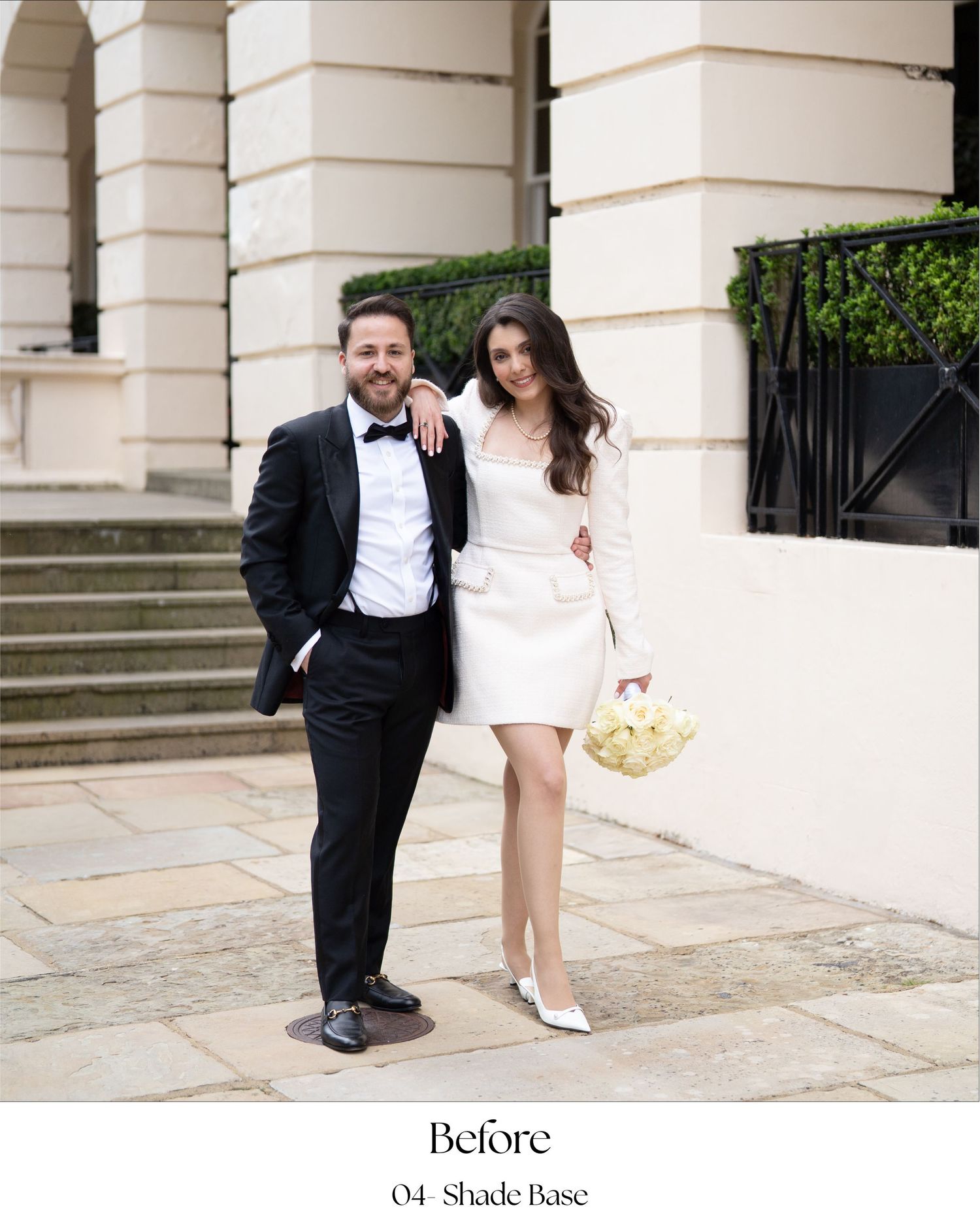 A couple in formal attire poses together on elegant stone steps of a historic building.