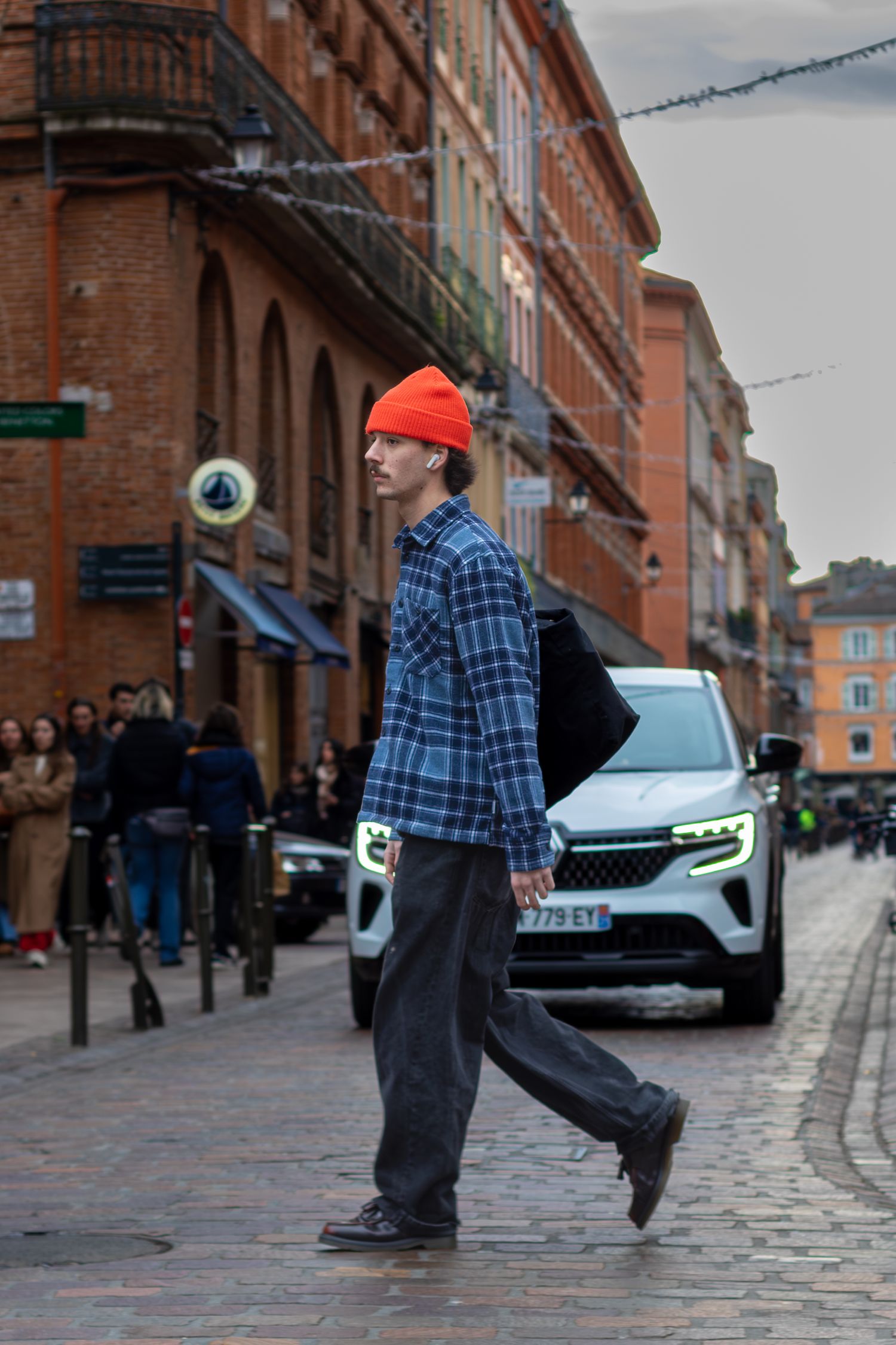 Un passant avec un bonnet rouge, en ville.