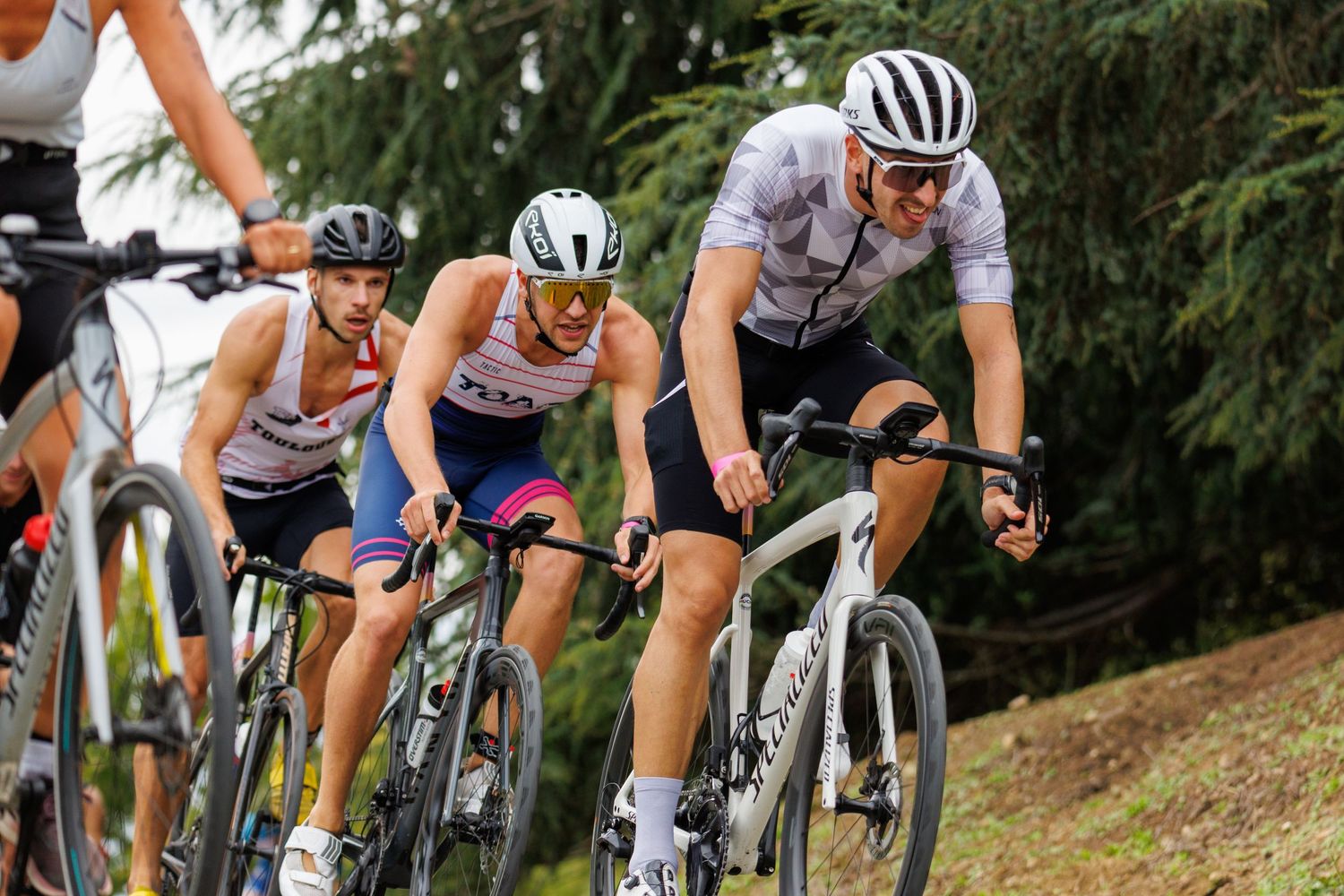 Cyclists in helmets and racing gear competing in an outdoor road cycling race.