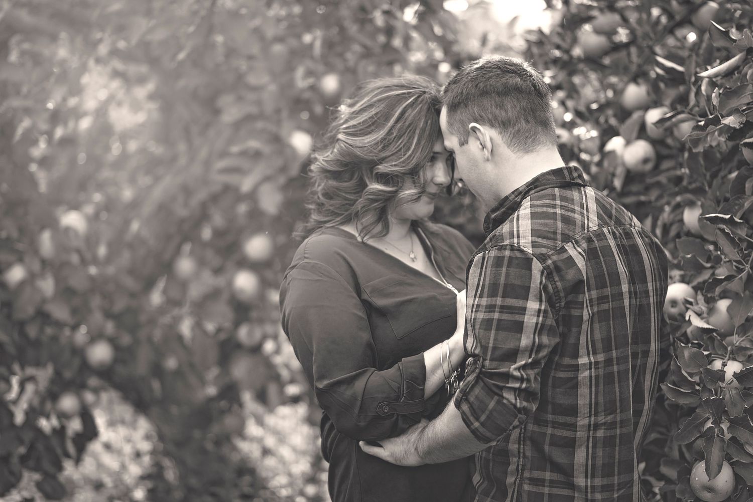 Black and white intimate portrait of couple in orchard setting.