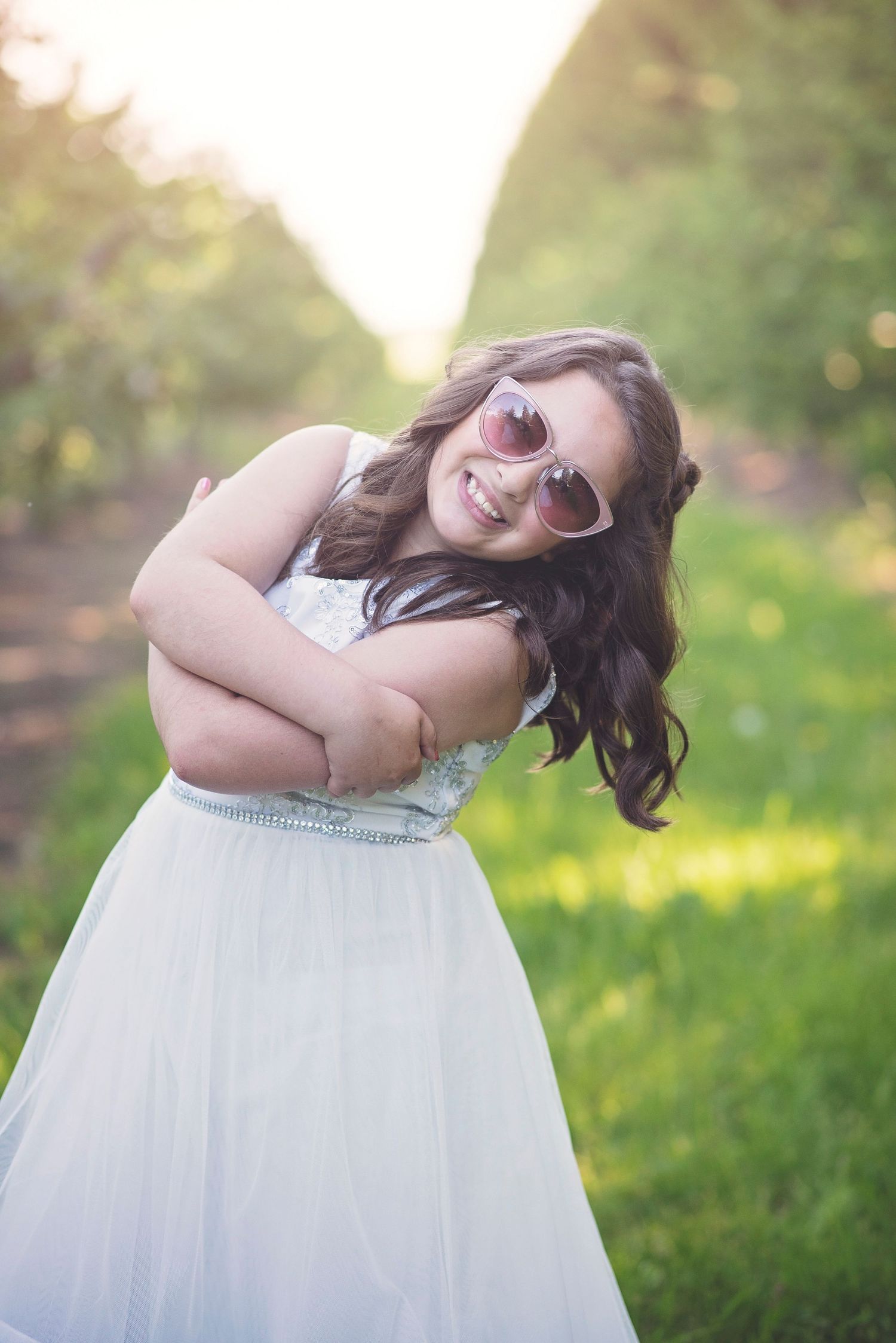 White dress and heart-shaped sunglasses create a playful summer portrait in golden sunlight.