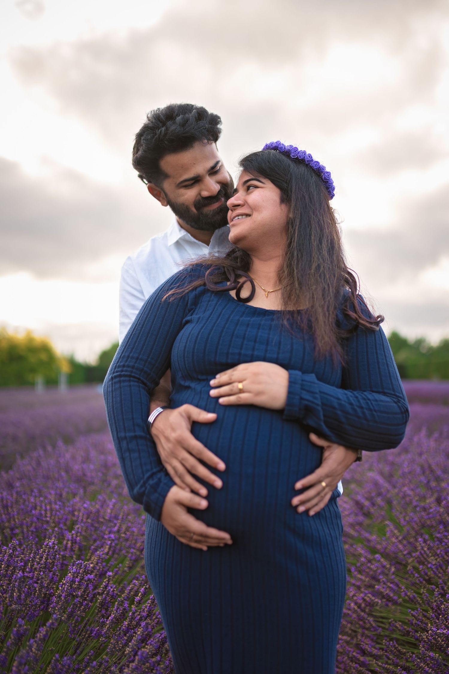 A couple shares an intimate moment together in a vibrant lavender field at sunset.
