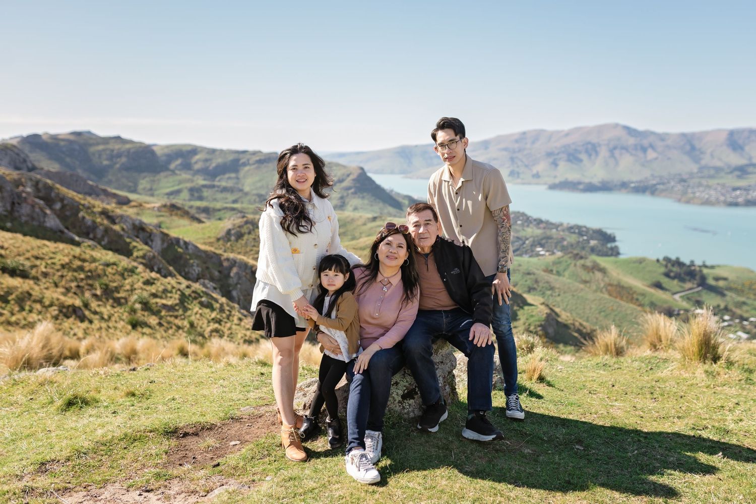Group of friends enjoying scenic mountain views while hiking along green hillsides in New Zealand.