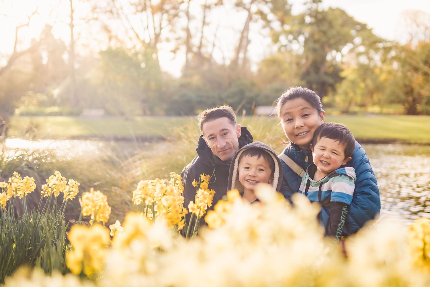 A family group poses together among blooming yellow daffodils in a spring garden.