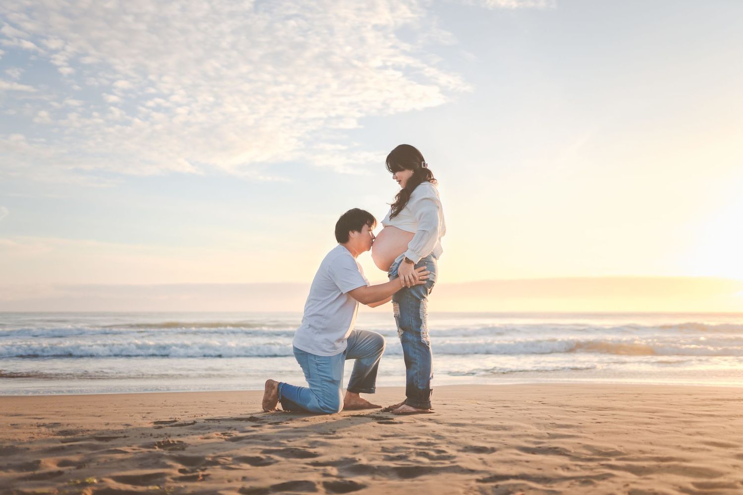 A romantic proposal scene on a beach at sunset with ocean waves in the background.