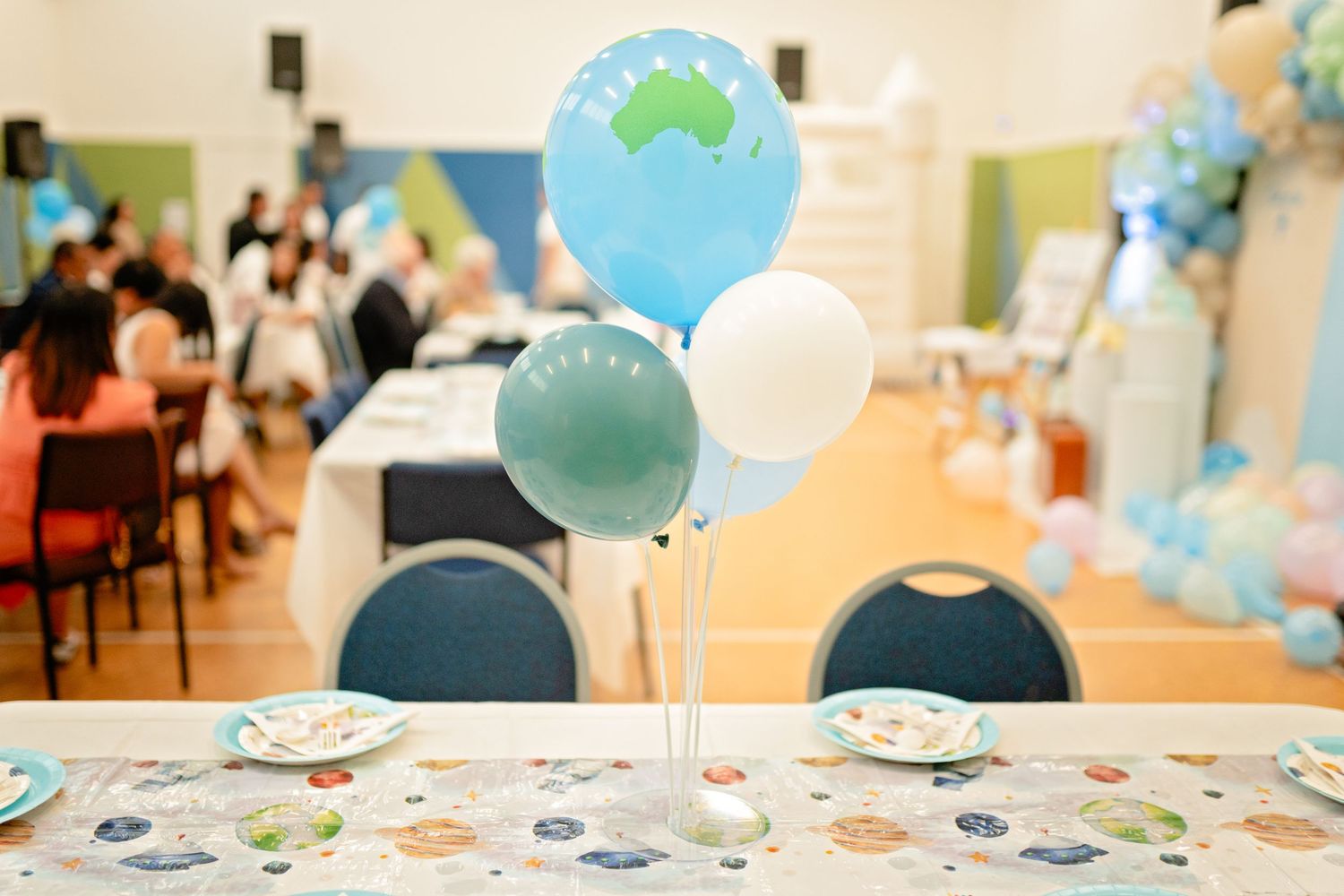 A party table decorated with blue and white balloons and patterned tablecloth for a celebration.