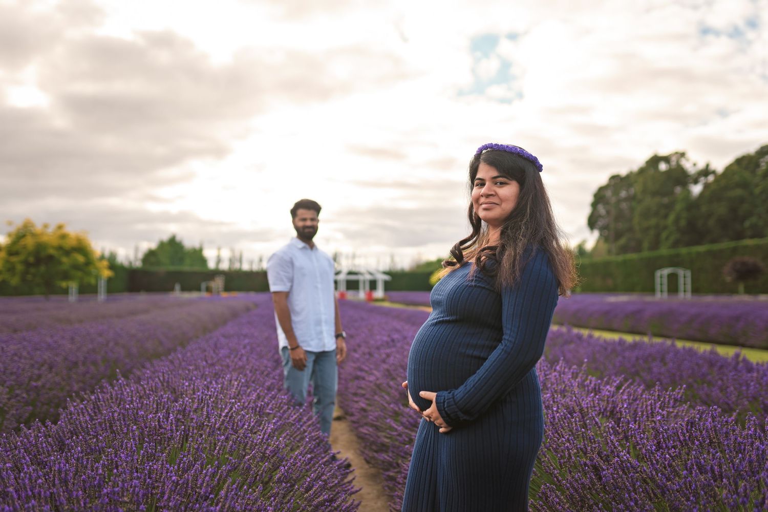 Expectant couple posing in a beautiful lavender field at sunset.