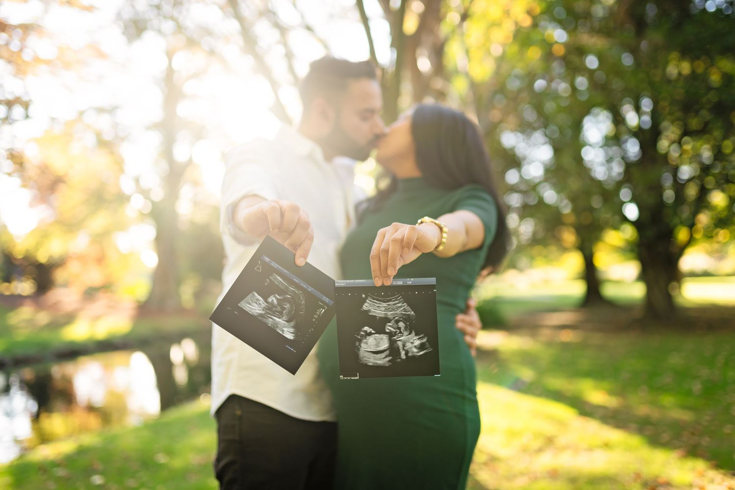 Couple holds coffee mugs together in dappled sunlight during a romantic autumn morning outdoors.