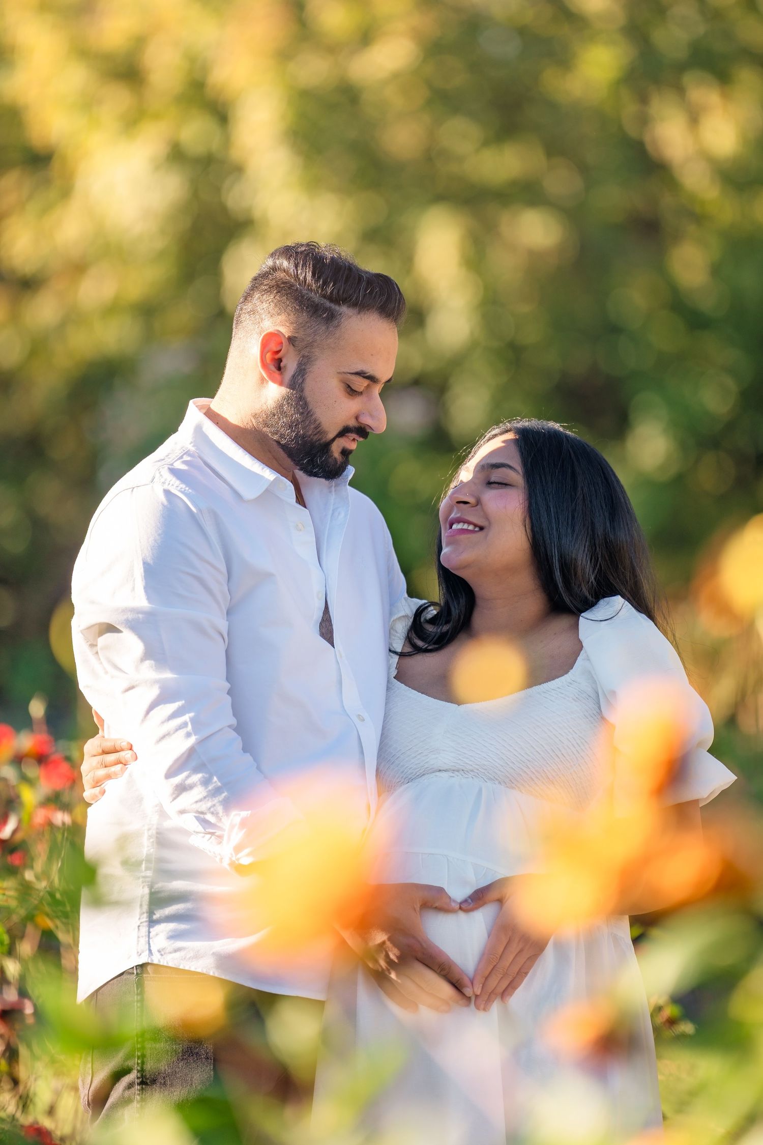 Couple sharing romantic moments outdoors with orange flowers in the foreground during golden hour lighting.