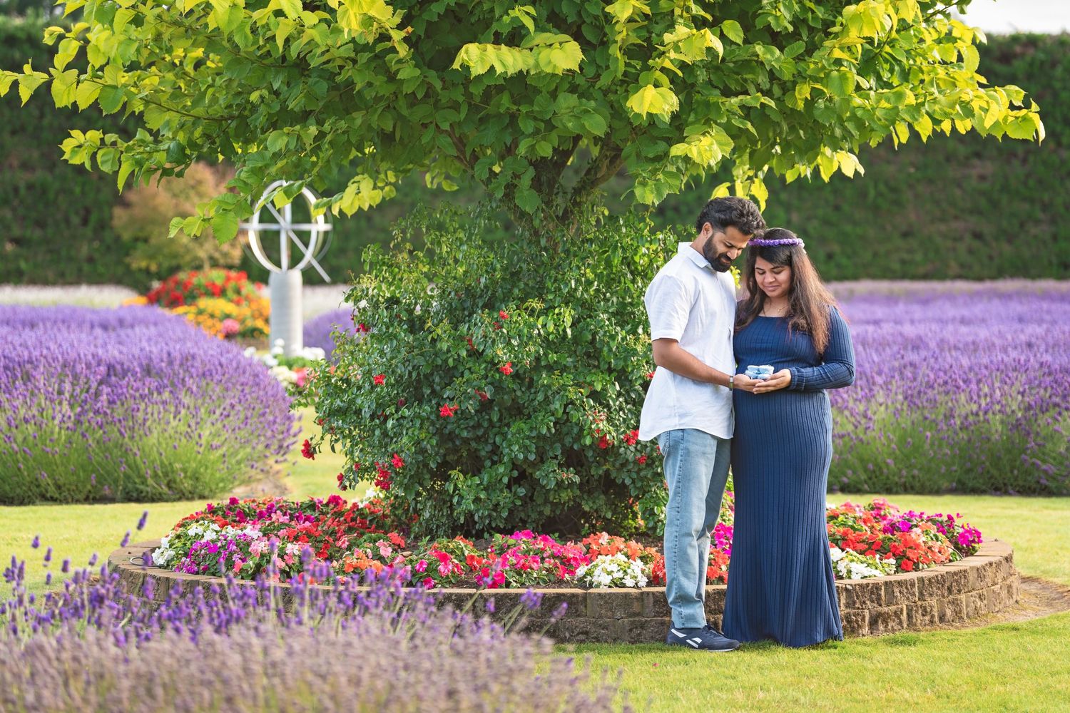 Couple embracing in a lavender garden during maternity photoshoot.