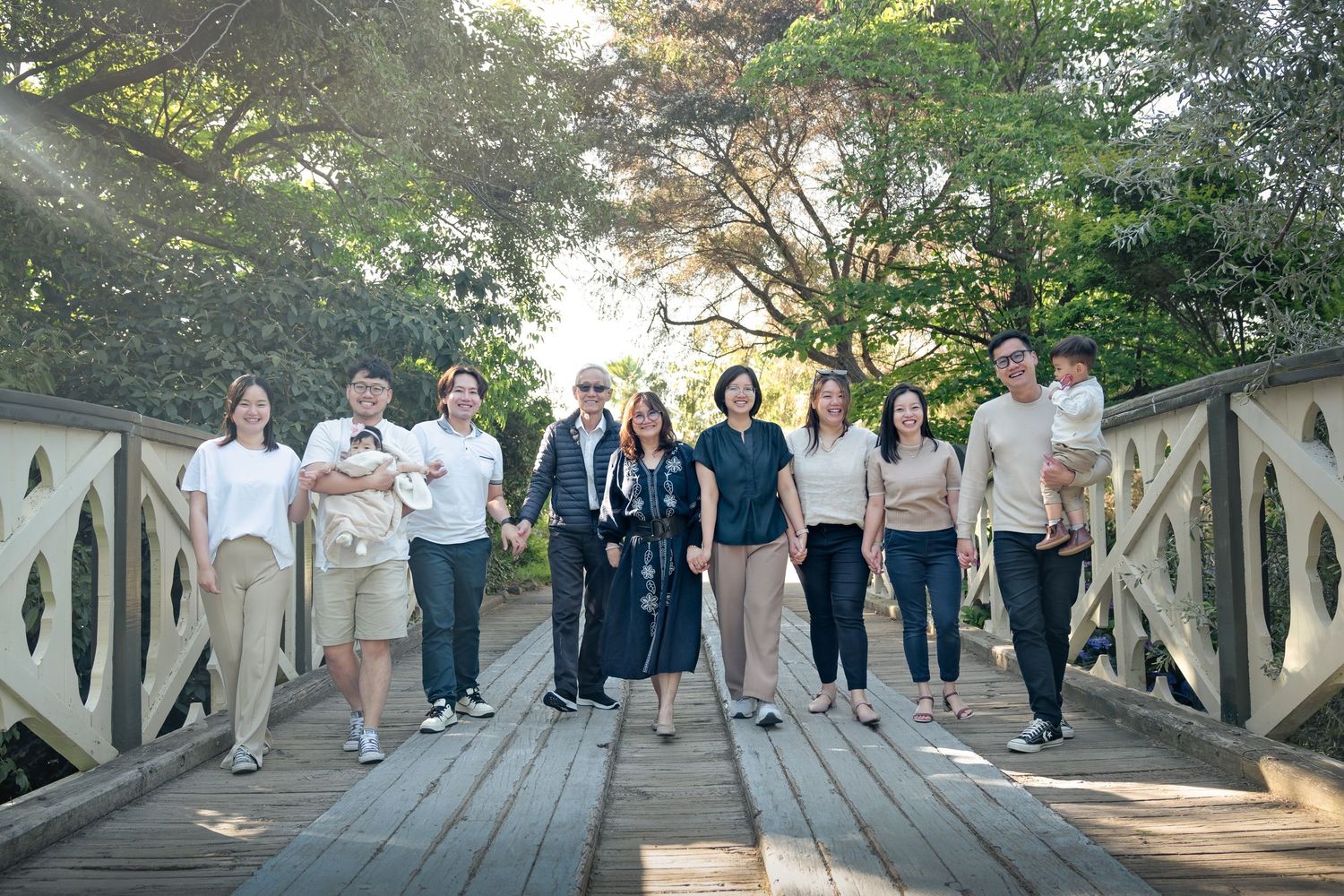 A group of people walking together on a wooden bridge walkway in a scenic outdoor setting during daytime.