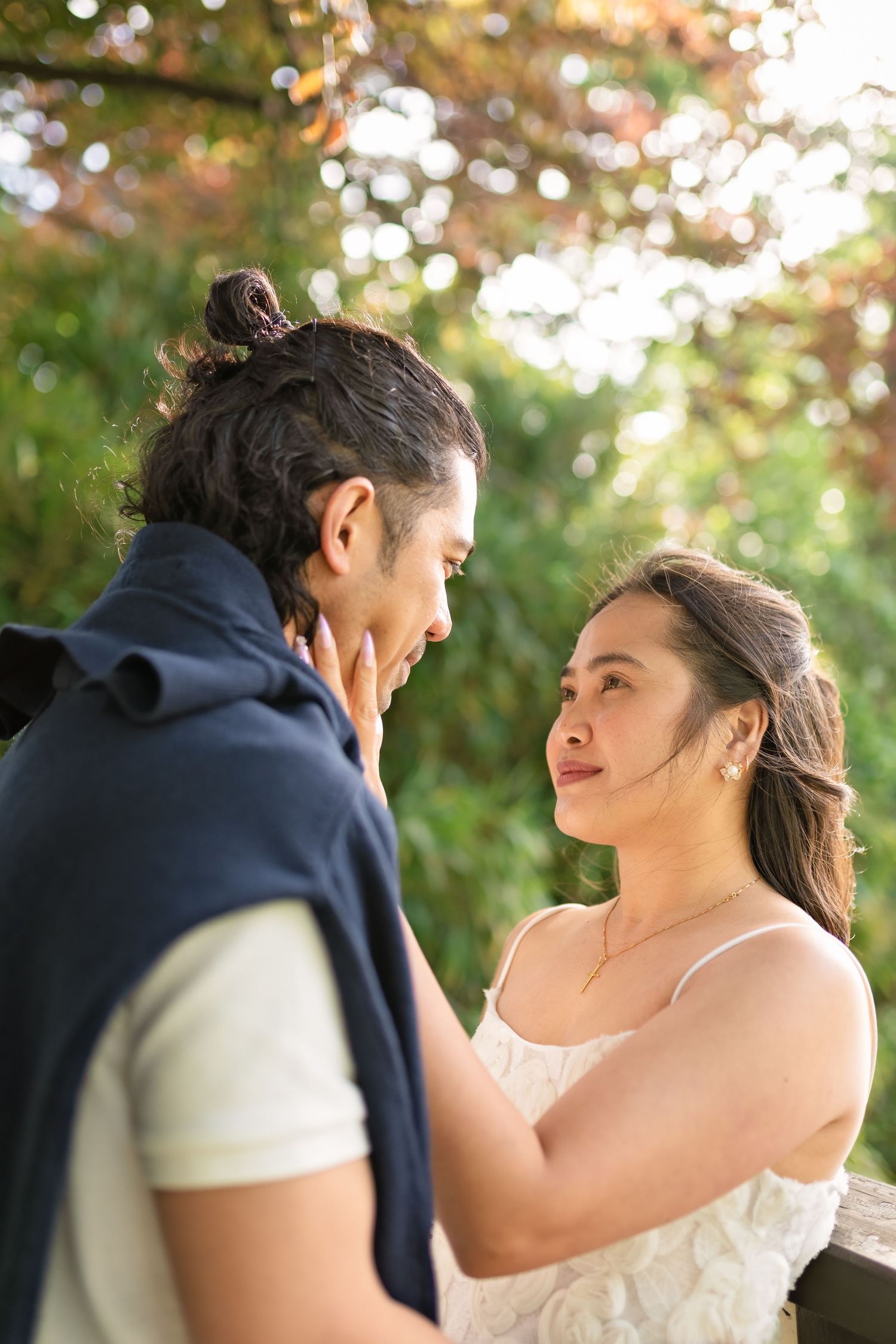 Couple gazing at each other tenderly outdoors among autumn foliage.