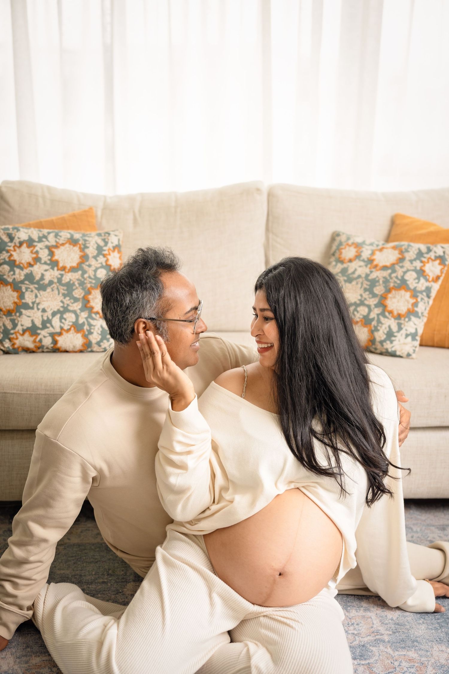A couple in cream-colored outfits sitting on the floor shares intimate moments across four progressive shots.