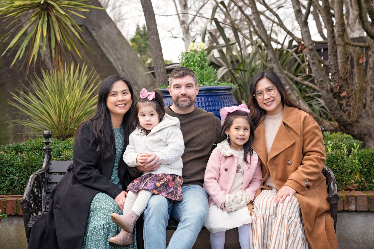 Family members pose together outdoors in a garden setting wearing coordinated casual outfits.