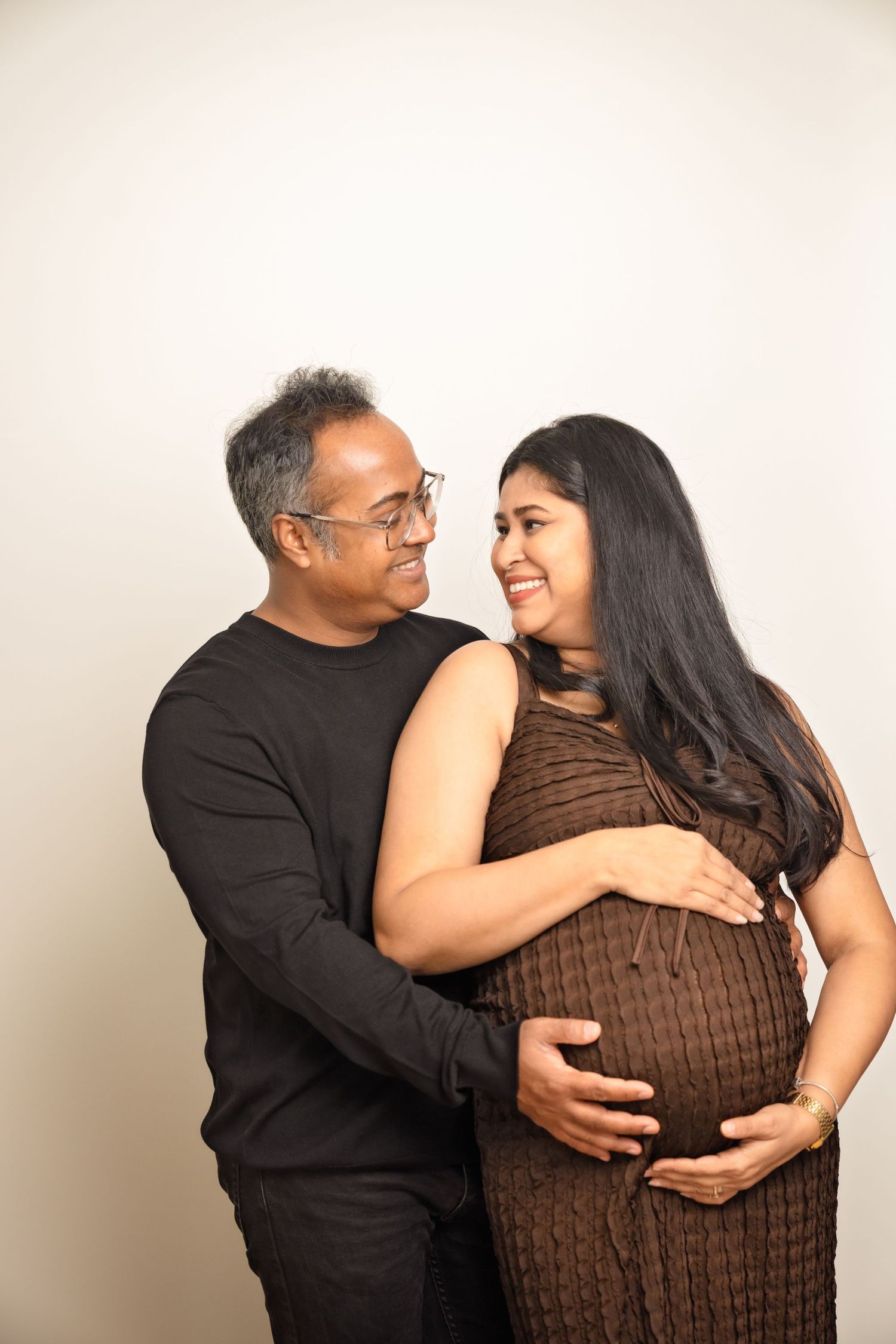 A series of four affectionate photos showing a couple in black and brown clothing embracing and smiling together.