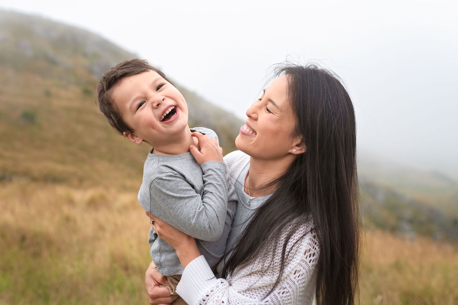 Candid moment of laughter and joy shared outdoors against mountain backdrop.