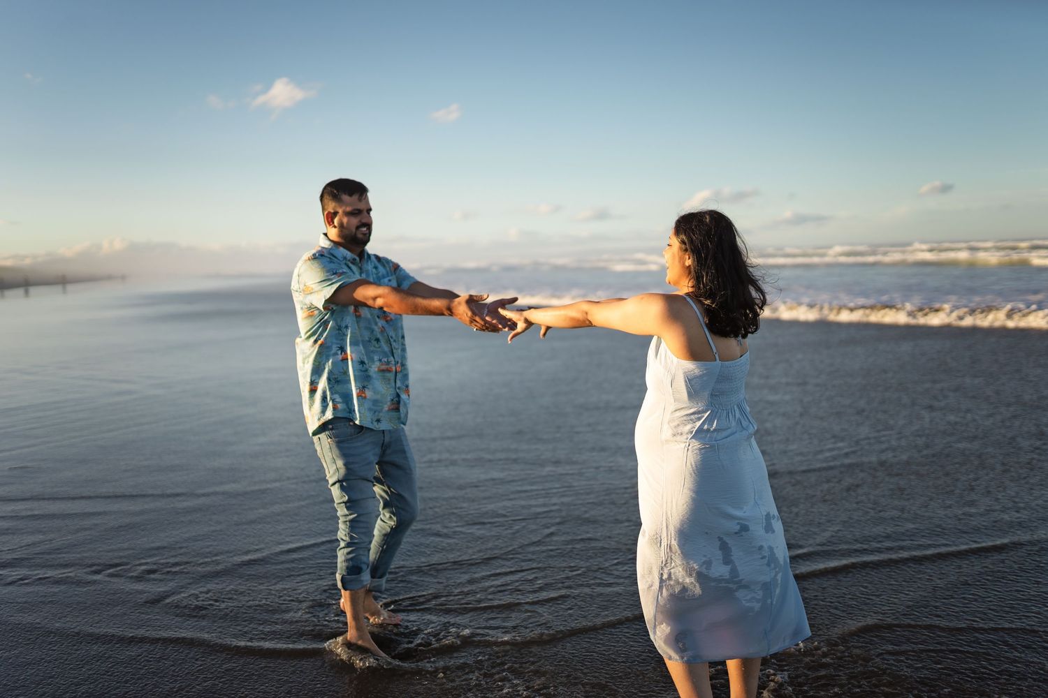 Panoramic series of people walking and playing along a scenic beach shoreline at sunset with mountains in background.