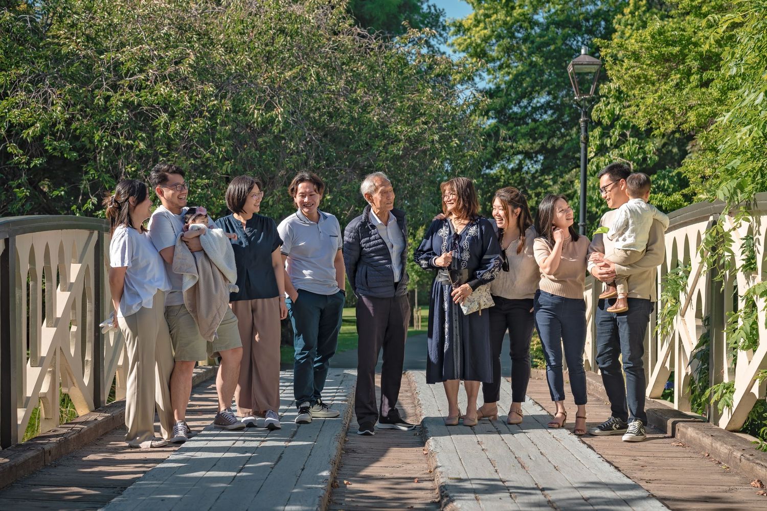 A panoramic view of wedding guests lined up along an outdoor walkway during a sunny daytime celebration.
