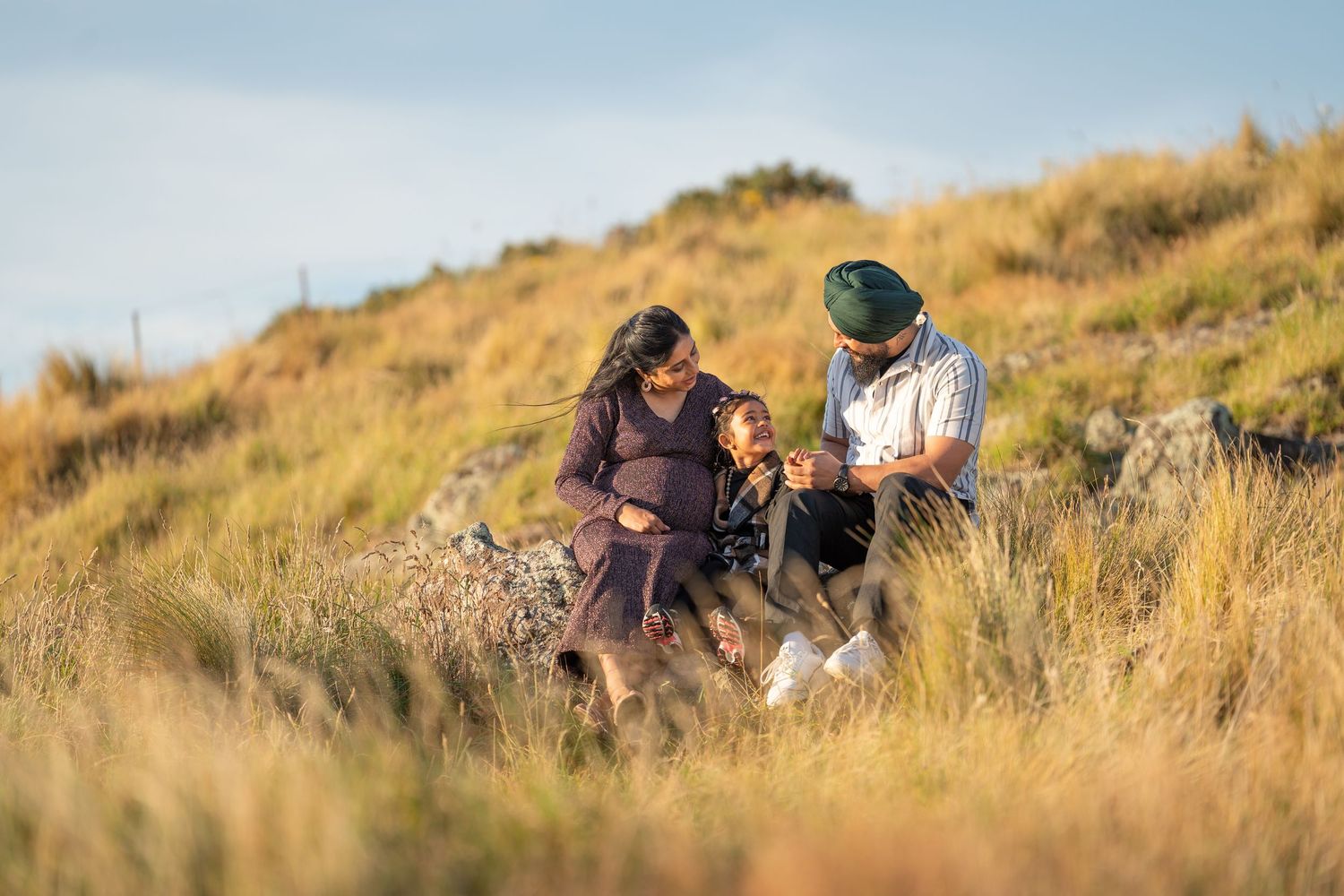 A couple shares a tender moment on a hillside during golden hour.