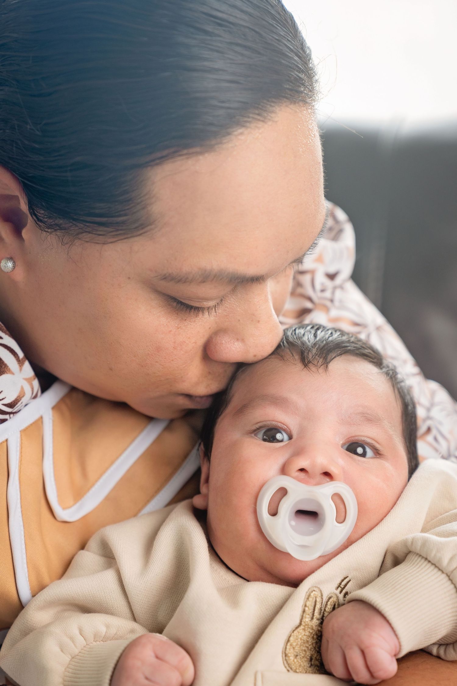 A tender moment is shared between parent and infant as they cuddle close, showcasing gentle nurturing and intimate bonding.