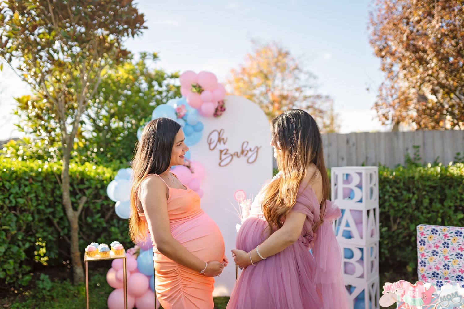 Outdoor gender reveal party decorated with pink and blue balloons capturing candid moments and celebrations at sunset.