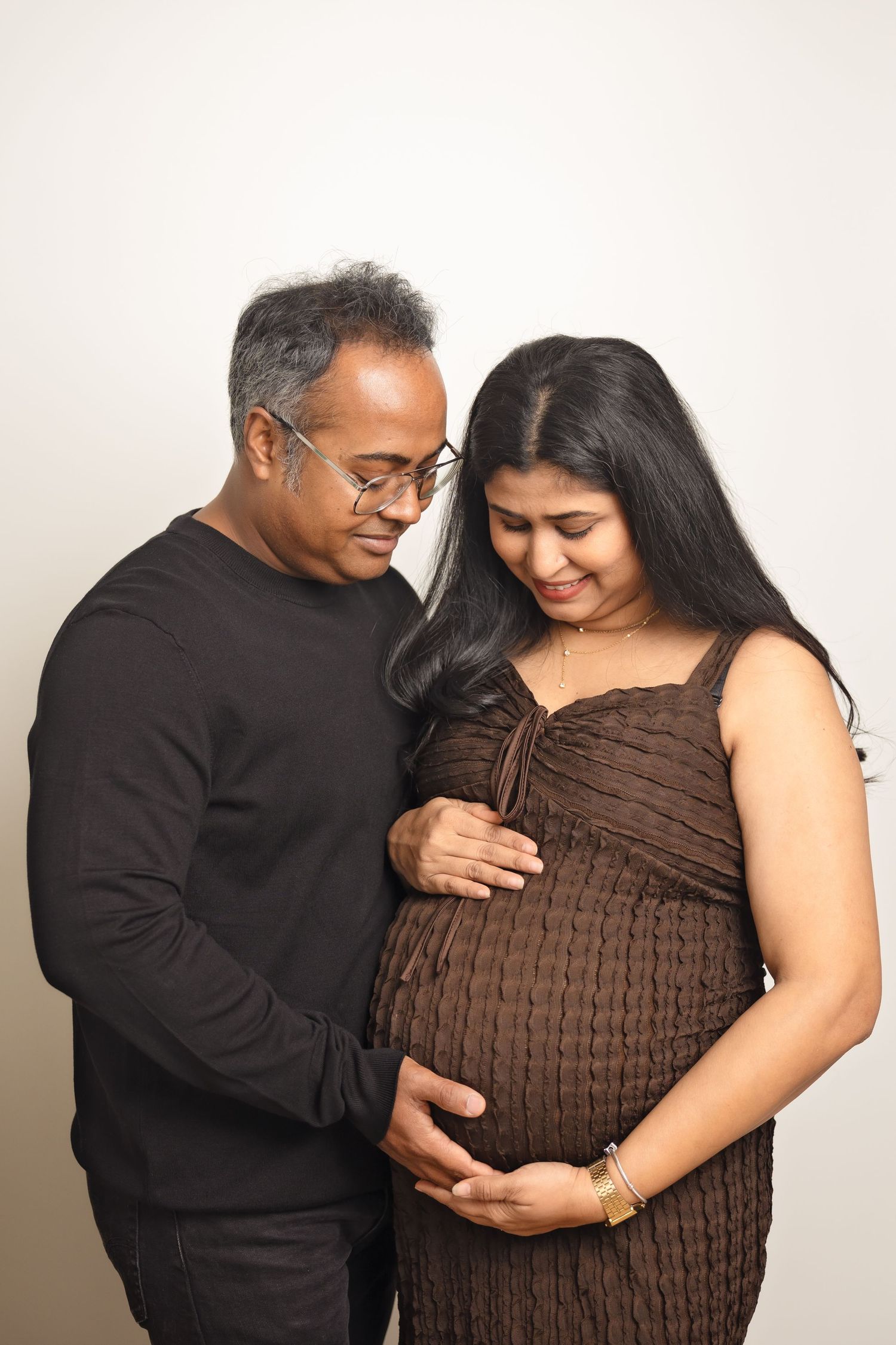 Four sequential photos showing tender maternity moments in brown dress and black top against light background.