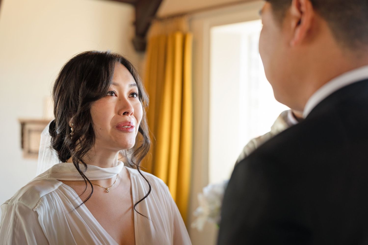 Asian bride gazing at groom during intimate wedding ceremony moment.