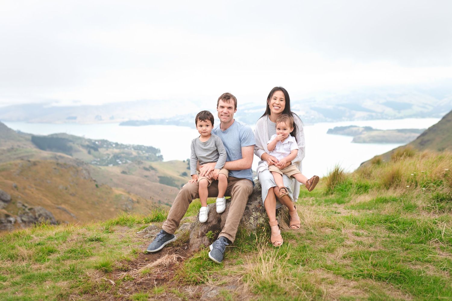 Family enjoying scenic mountain views while sitting together on grassy hillside.
