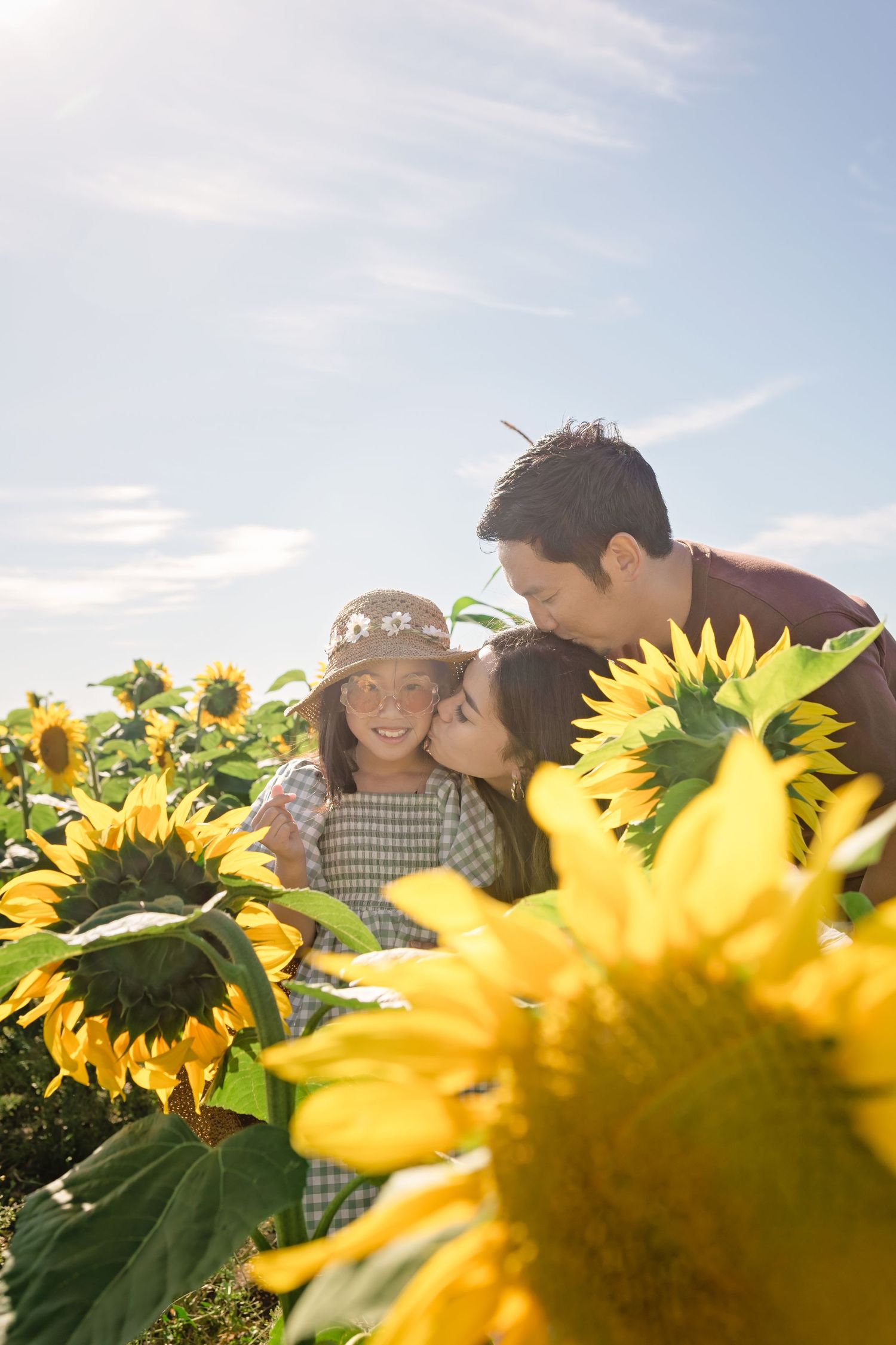 Three people sharing a joyful moment among bright yellow sunflowers in a sunny field on a beautiful summer day.