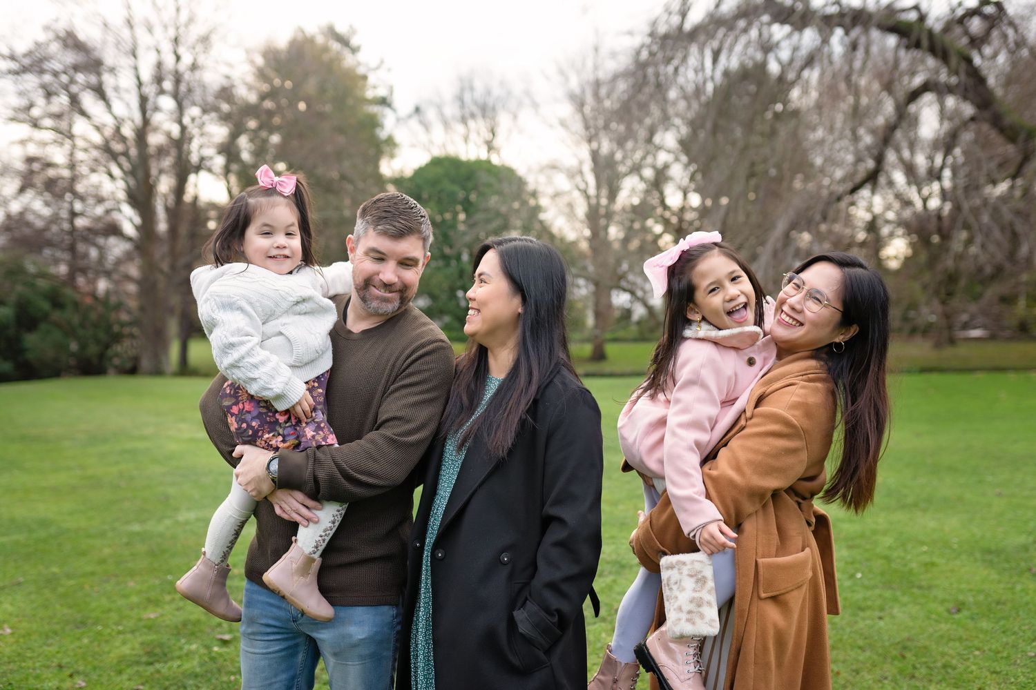 A group of people enjoying a candid moment together in a lush green park setting during golden hour.
