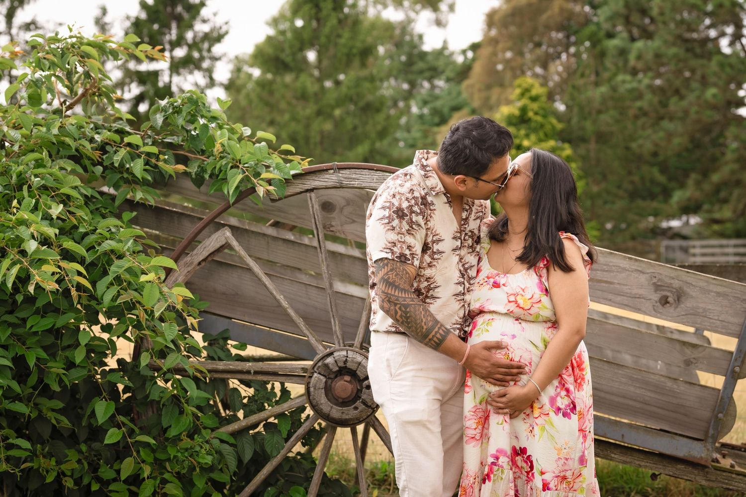 A couple shares an intimate moment in front of rustic wooden fencing during an outdoor photoshoot.