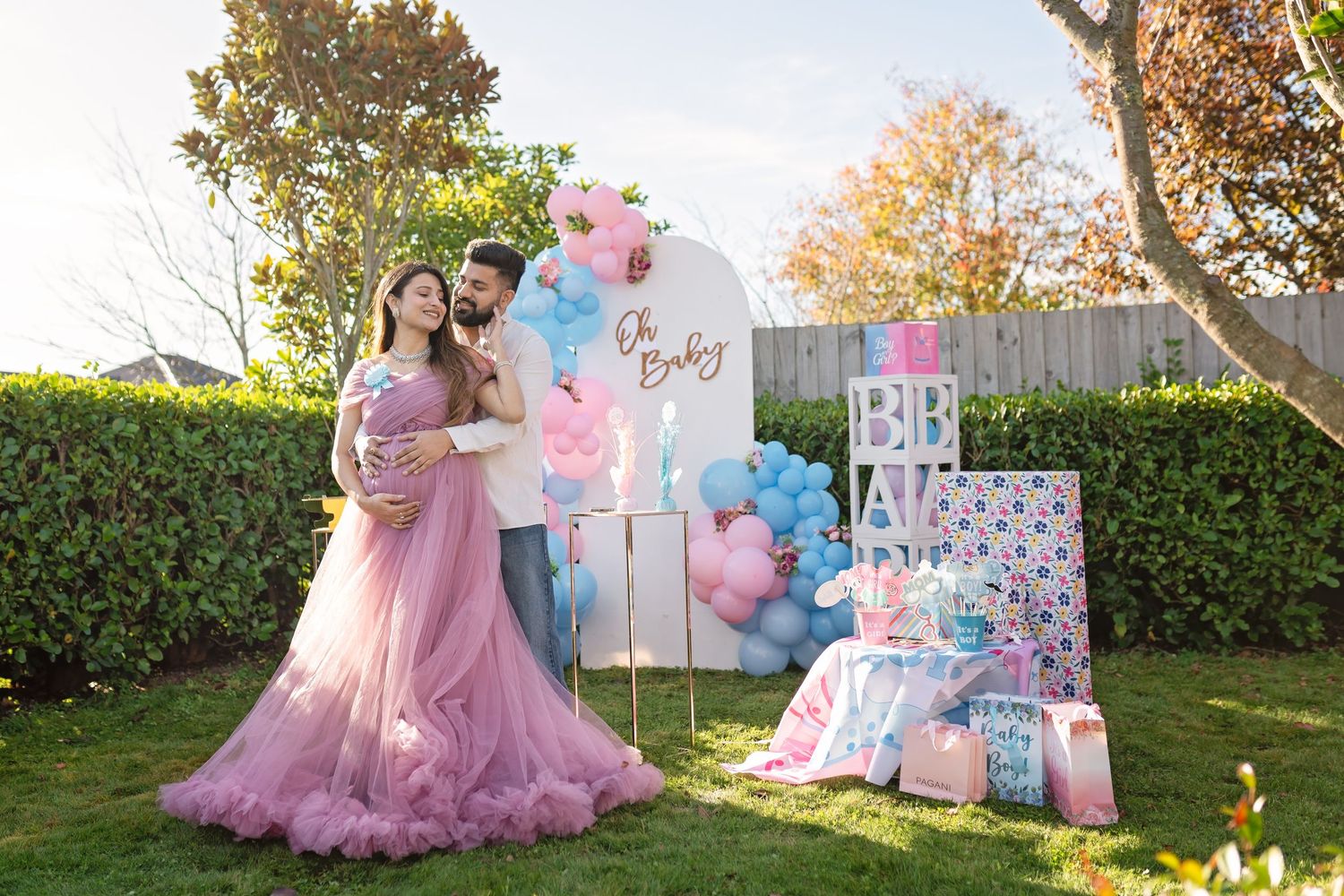 A charming outdoor gender reveal party setup with pink and blue balloons, floral decorations, and pastel decor displays.