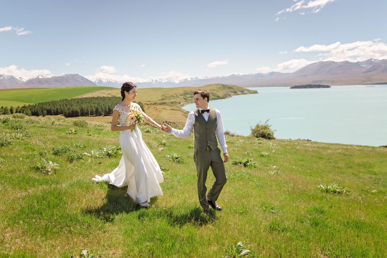 A couple walks through scenic mountain meadows near a lake on their wedding day, captured in multiple romantic poses.