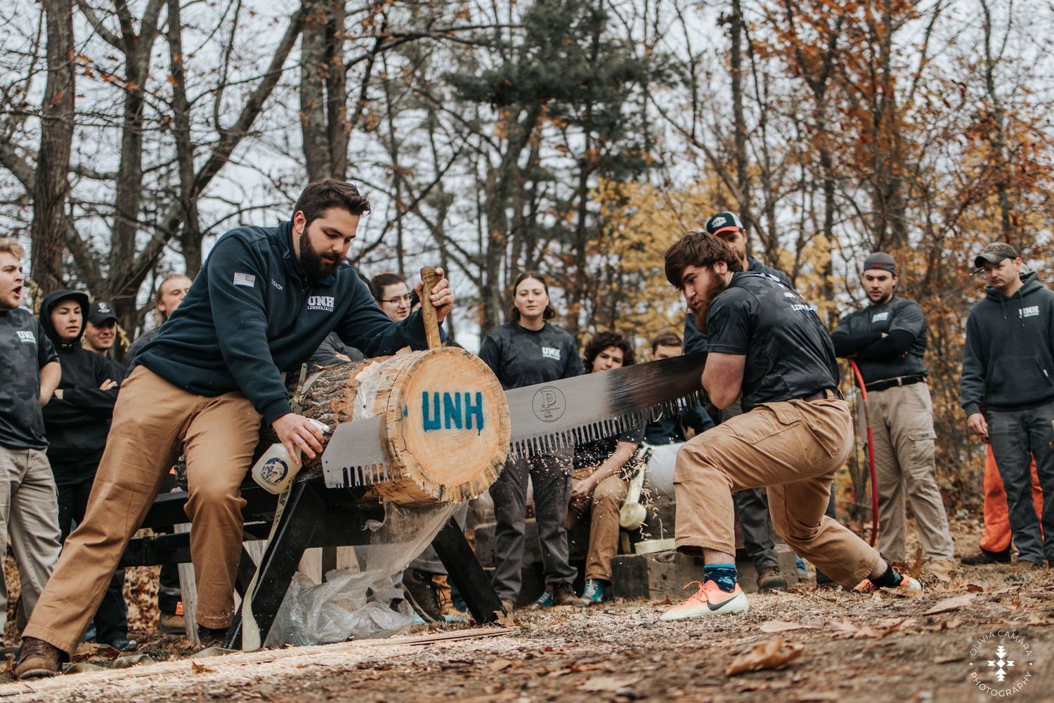 People gathered at an outdoor autumn event with fallen leaves on the ground.