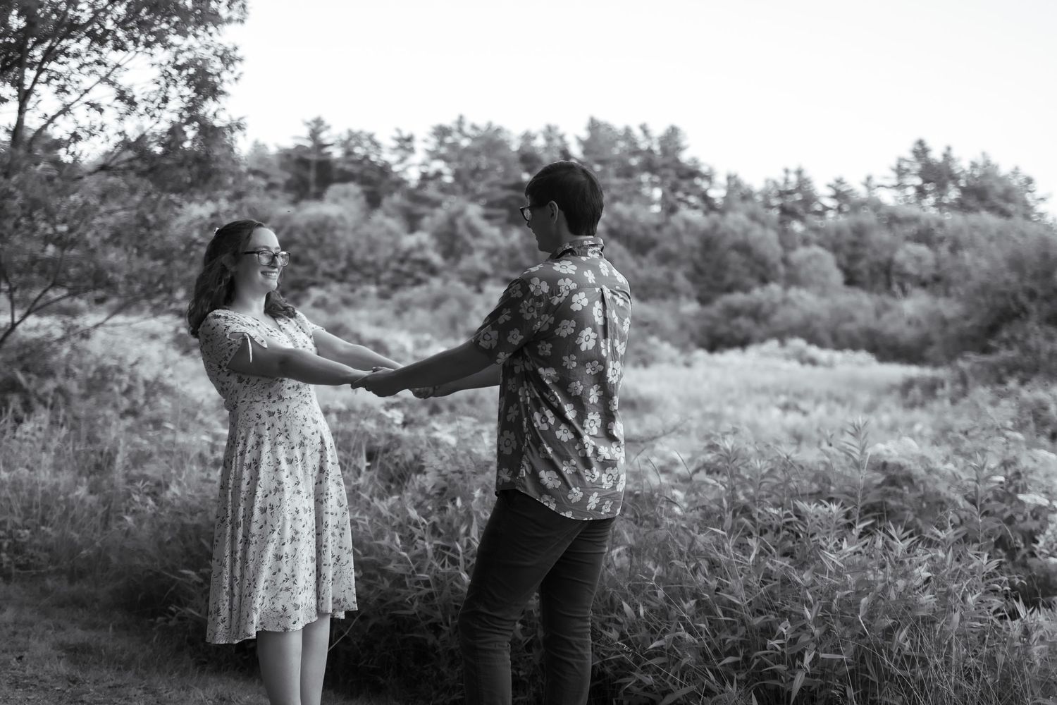 A couple shares a tender moment in a field of tall grass during golden hour.