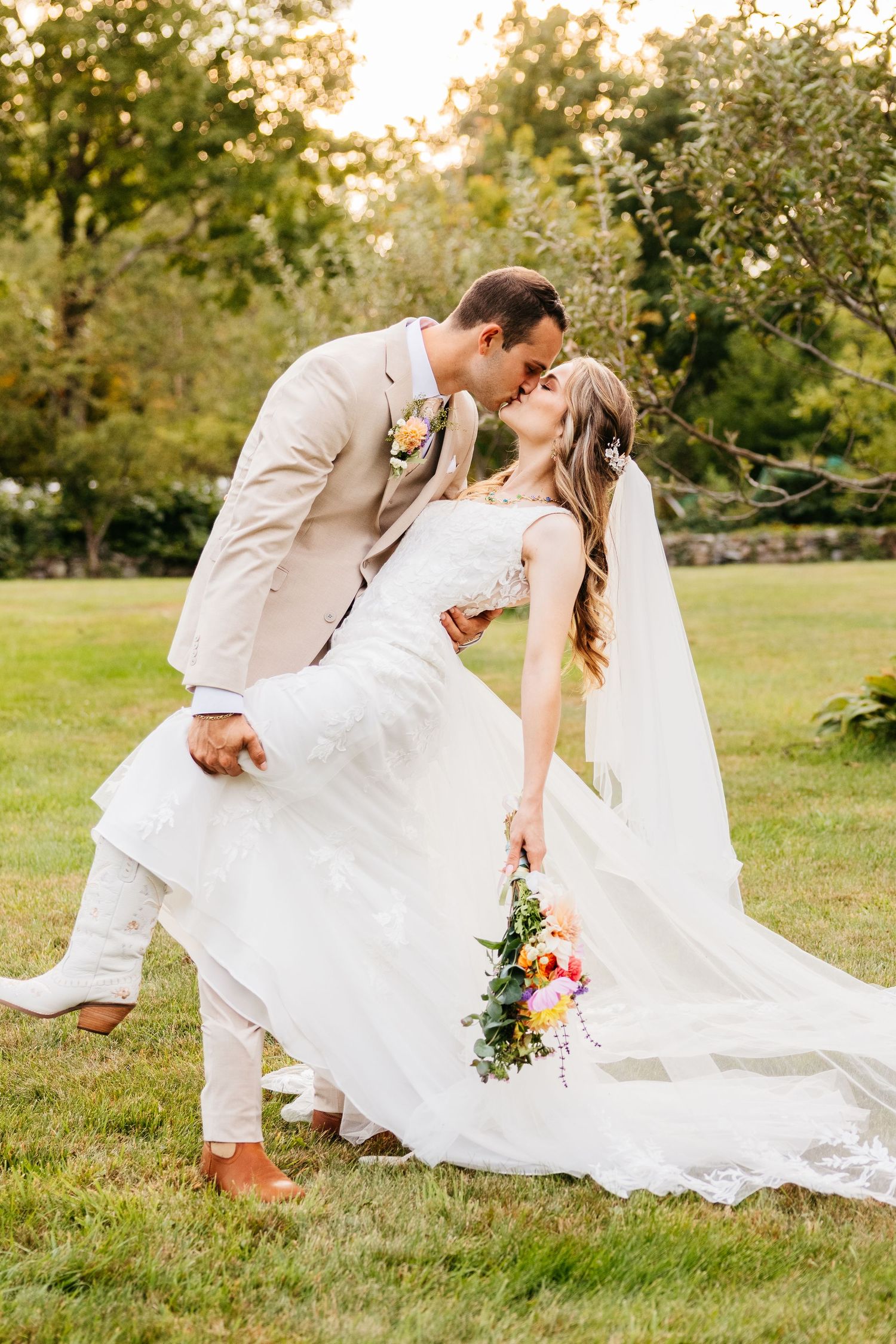 A romantic dip pose sequence of a bride and groom in formal wedding attire on a sunlit grassy lawn.