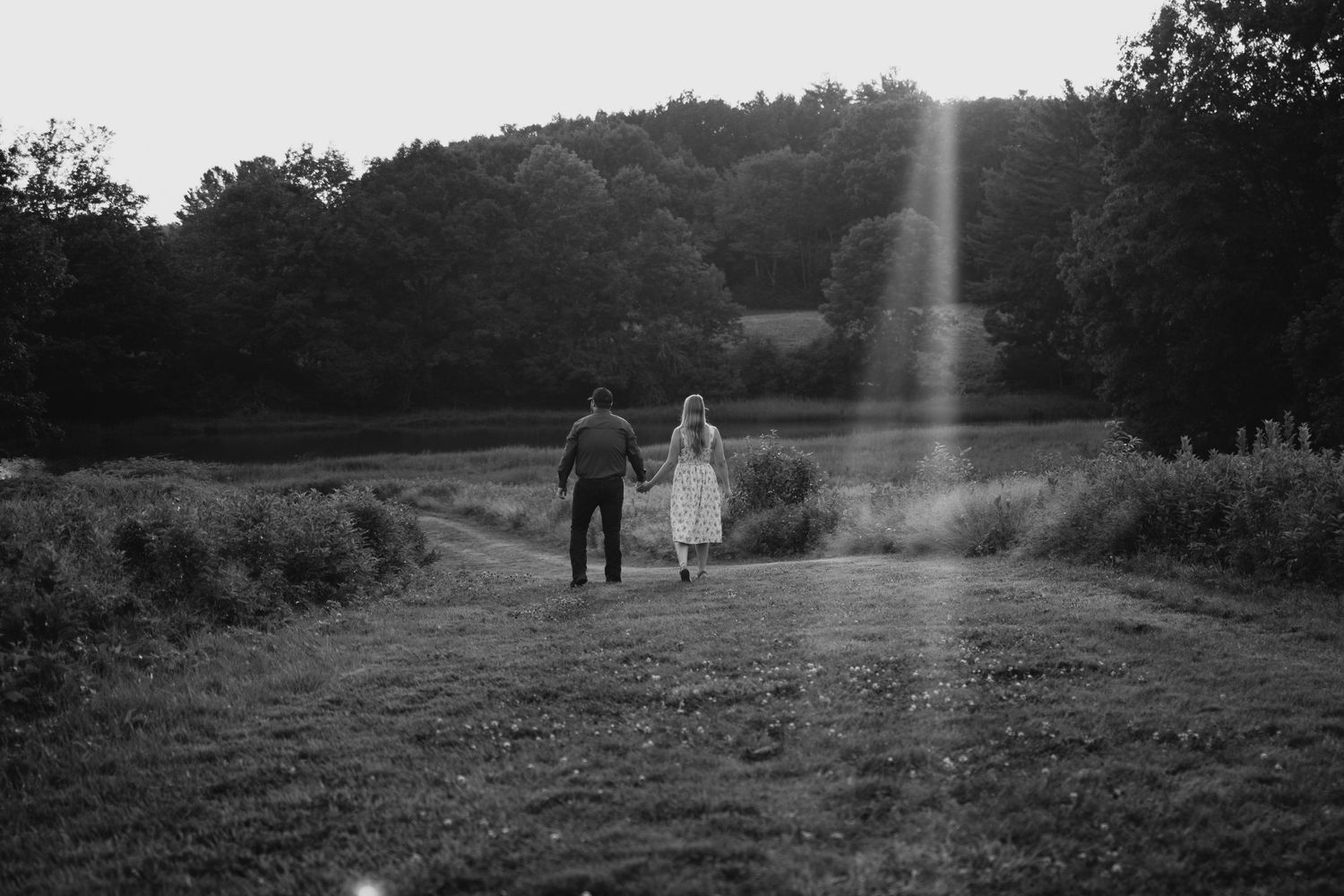 A series of black and white landscape photographs showing silhouettes of people walking through rural fields at sunset.