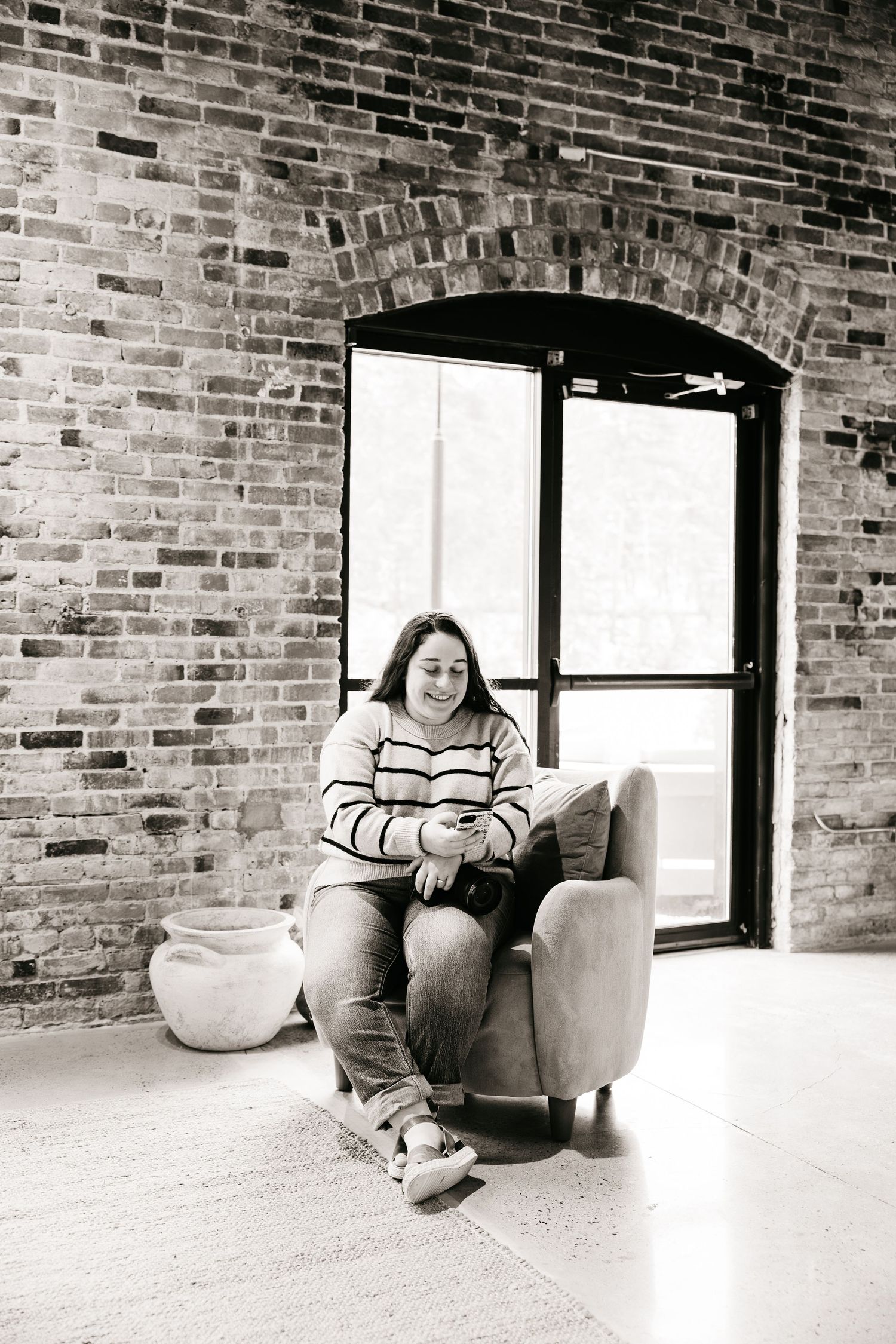 A triptych of black and white photos showing someone relaxing in an armchair against an exposed brick wall near windows.