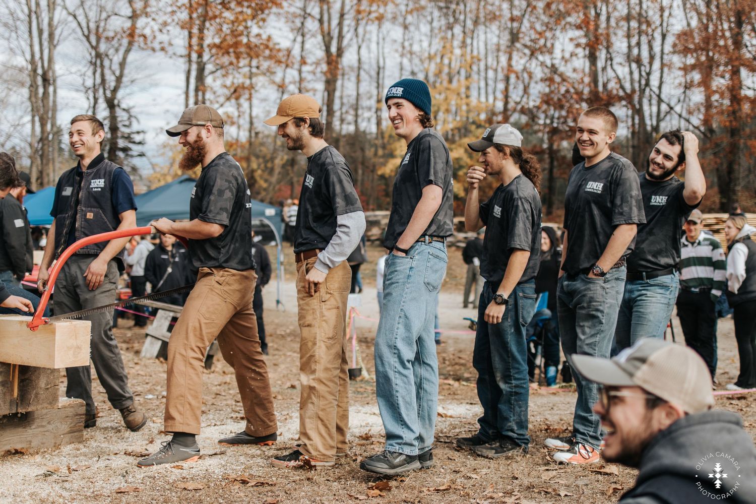 People gathered outdoors in casual attire during a fall event with bare trees in background.