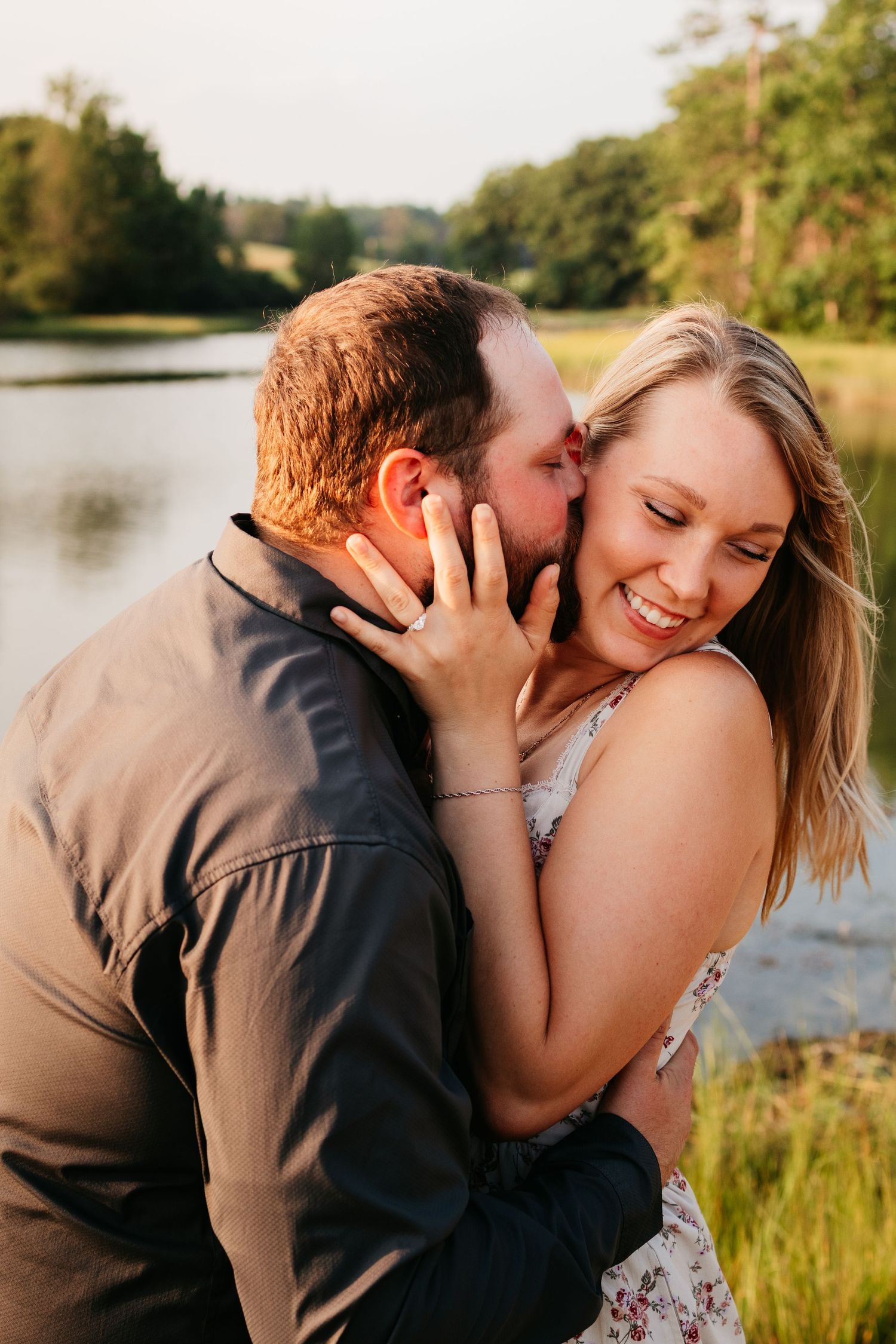 A romantic couple shares tender moments by a serene lake during a golden hour photoshoot.
